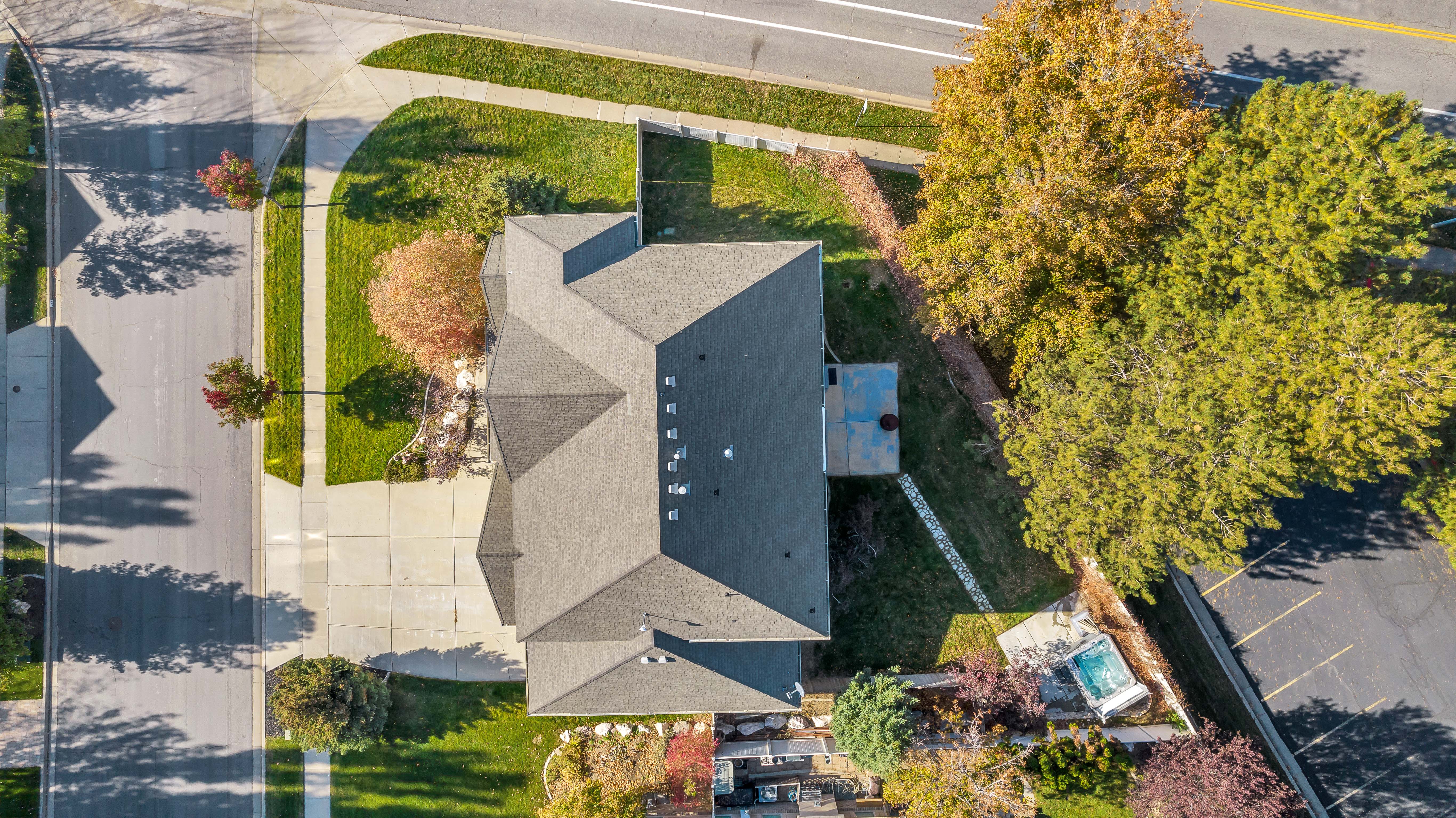 Aerial overview showcasing a property with a multi-gabled roofline, a paved driveway, and established landscaping