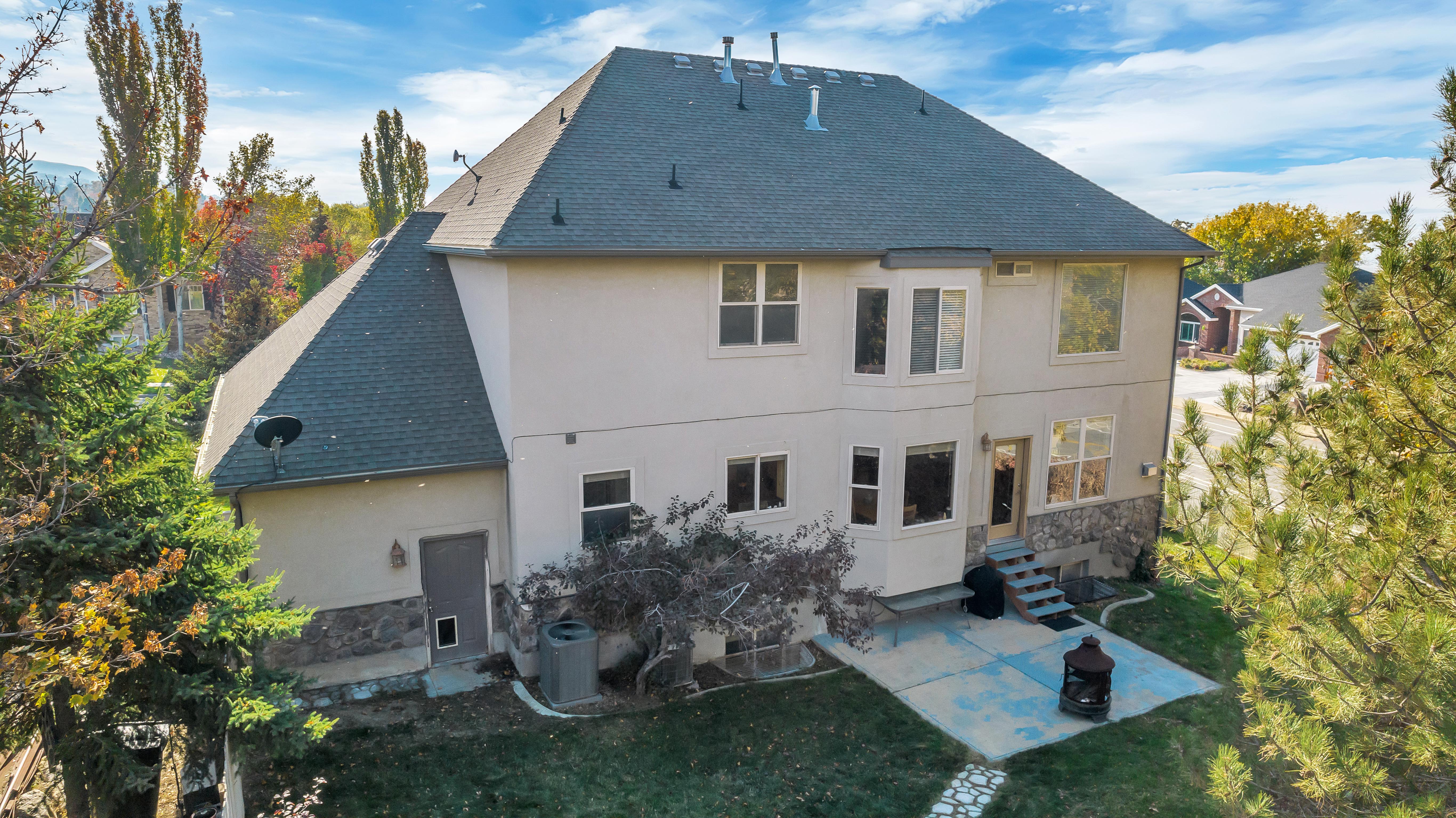 Rear exterior featuring a multi-level design with a stucco and stone veneer finish