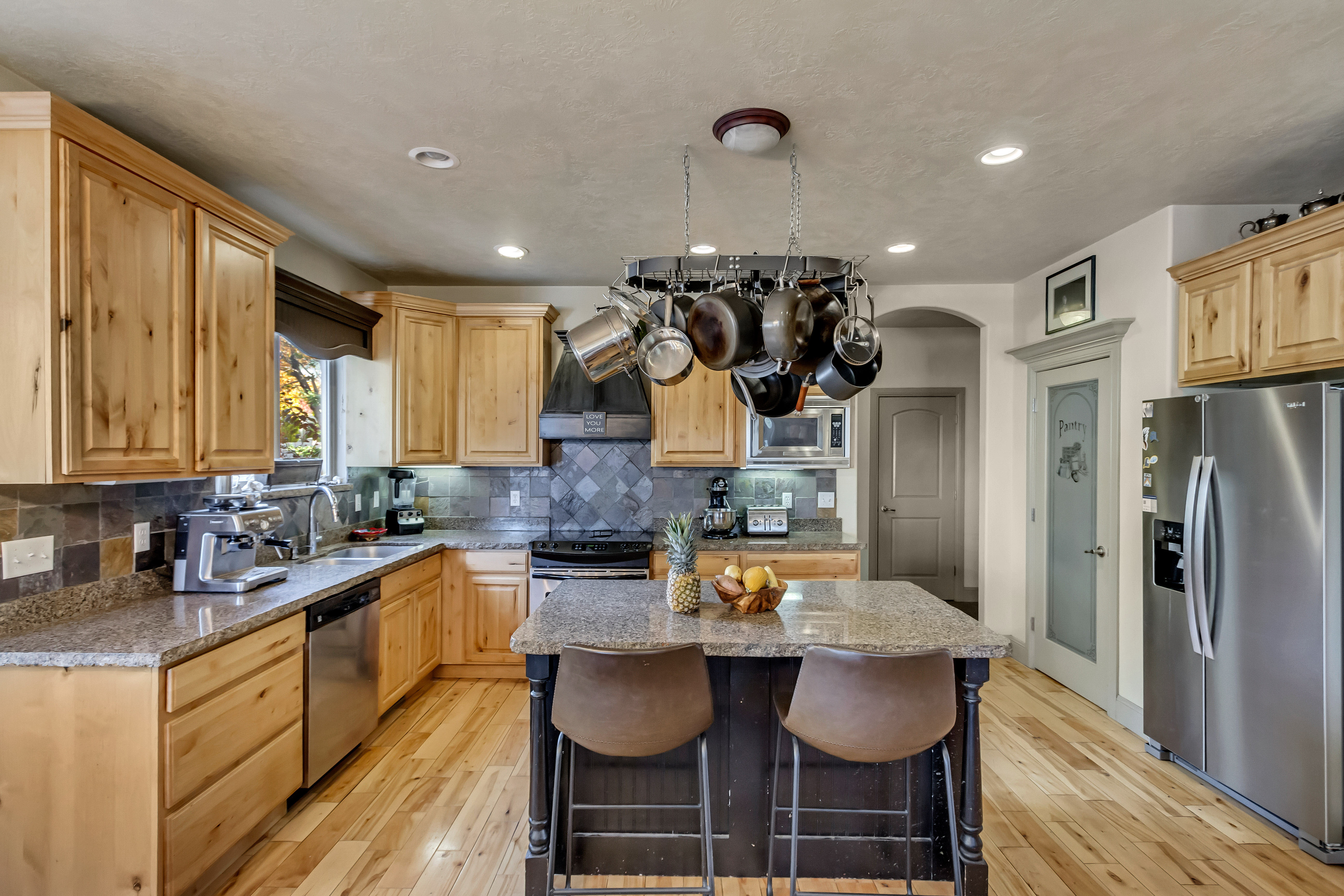 Kitchen featuring wood-finish flooring, granite countertops, and light wood cabinetry