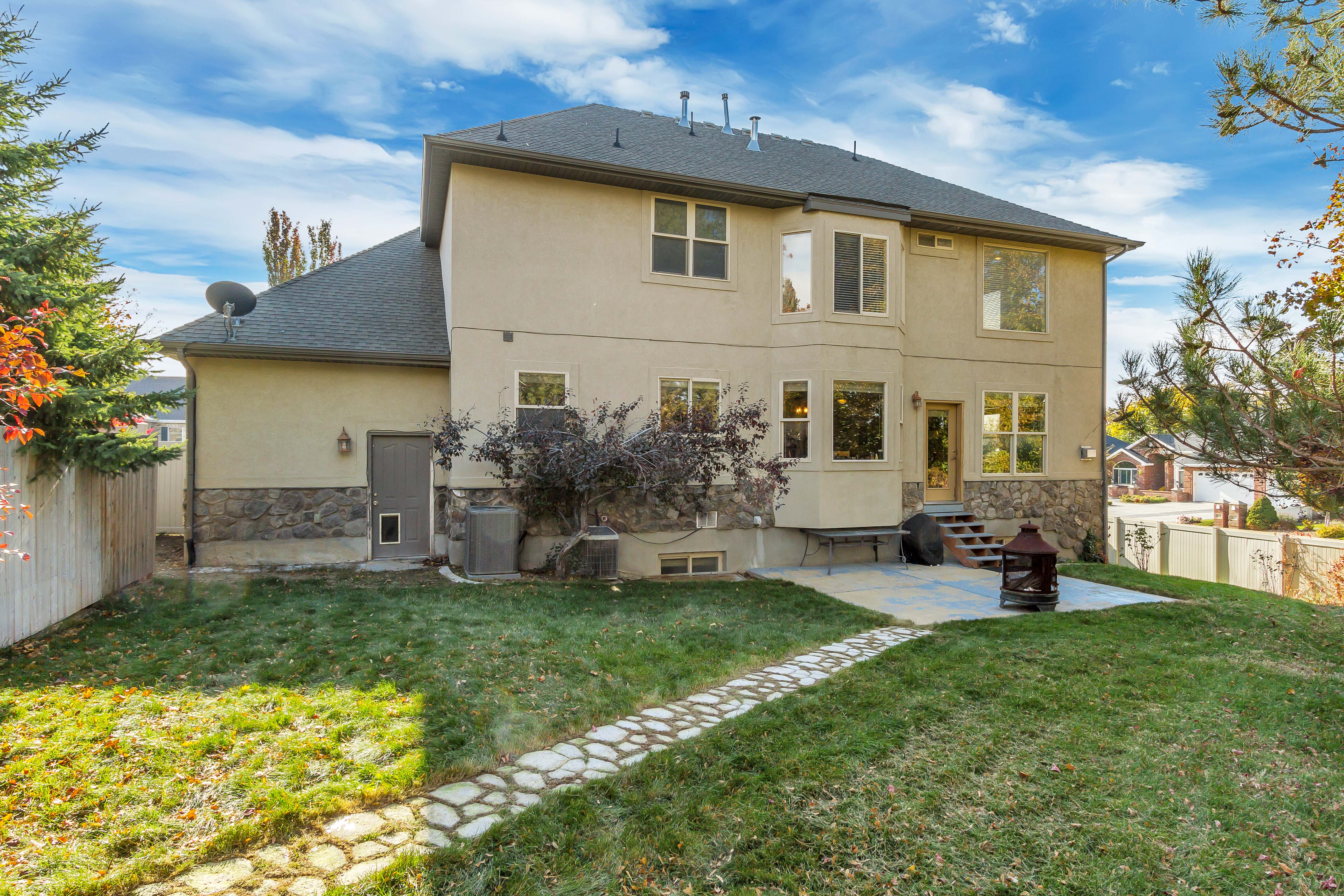 Rear exterior with stucco and stone veneer, featuring a multi-level design and a shingled roof