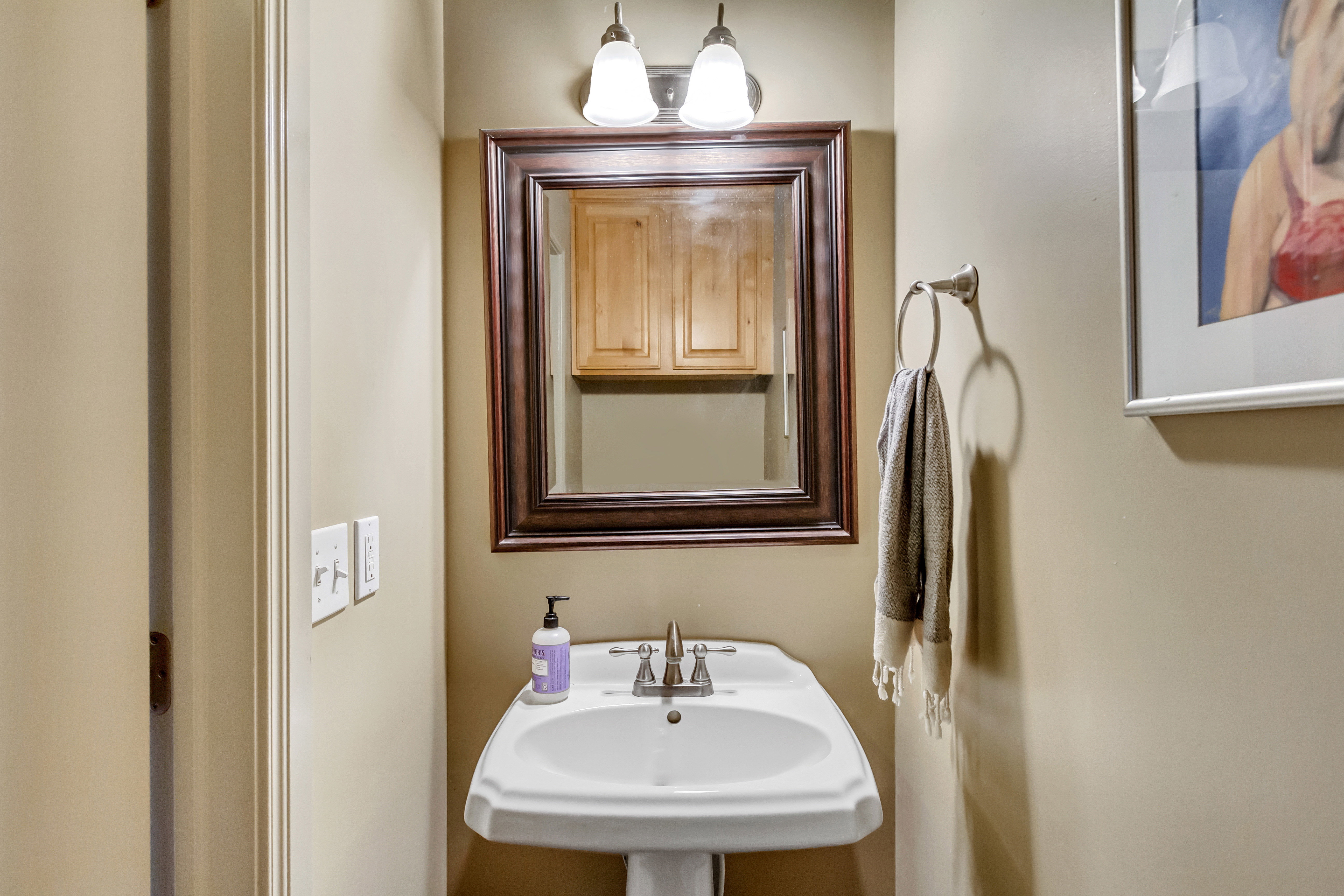 Pedestal sink with polished chrome faucet and a framed mirror