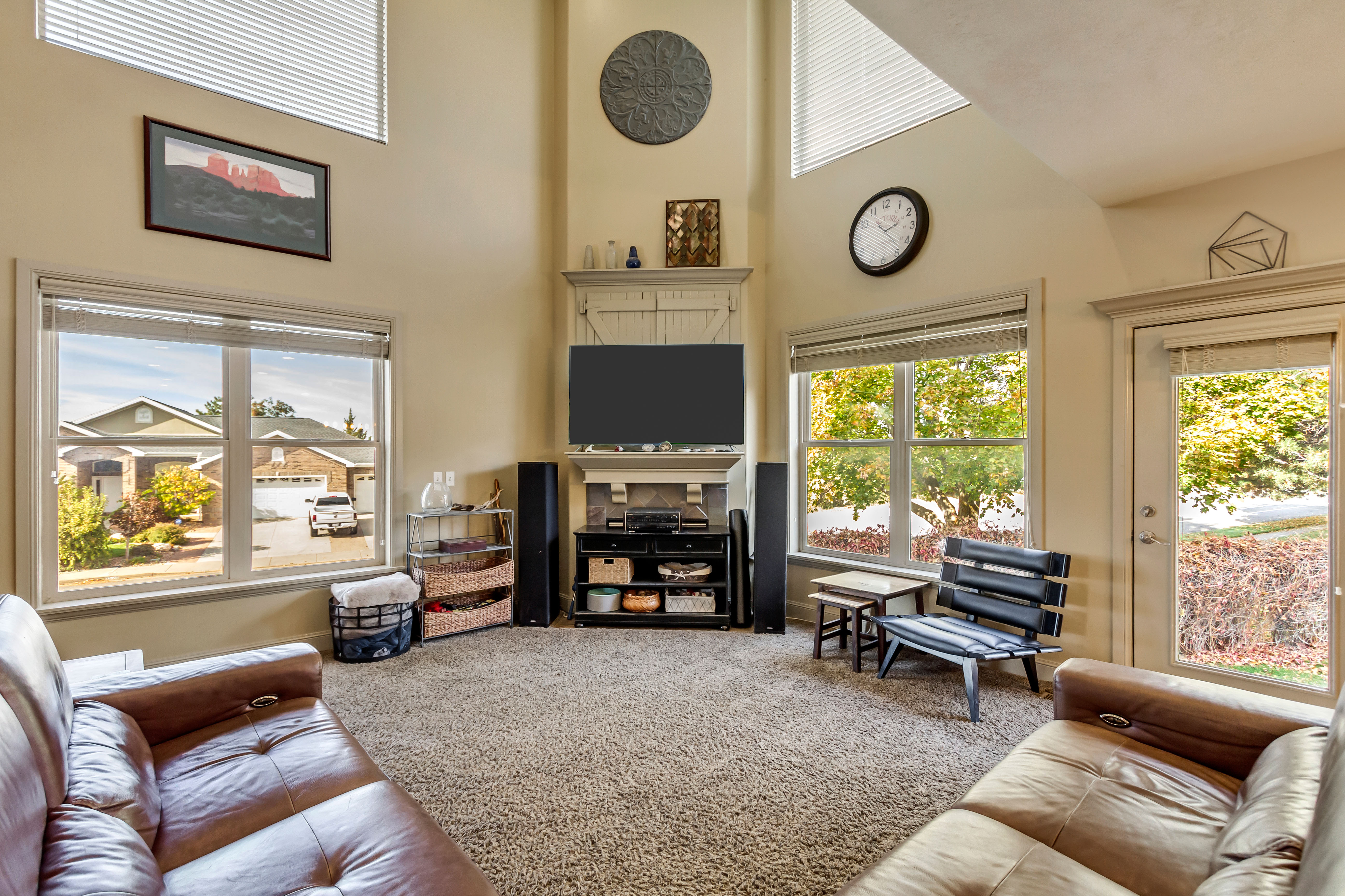 Living area featuring vaulted ceilings, abundant natural light from multiple windows, a corner media center with built-in cabinetry, and neutral-toned carpeting