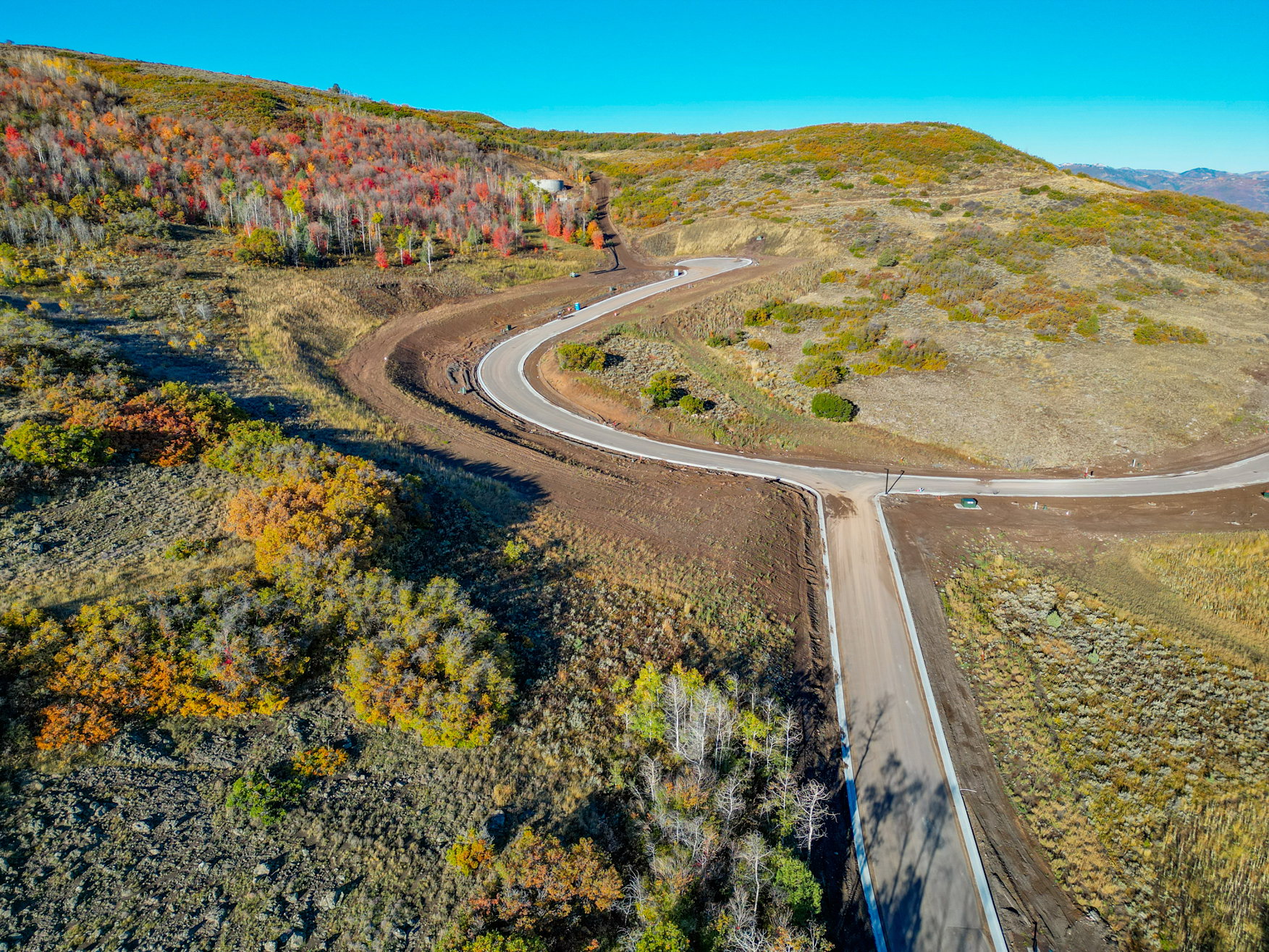 Newly paved roads traversing a sloped, undeveloped natural landscape with varied foliage
