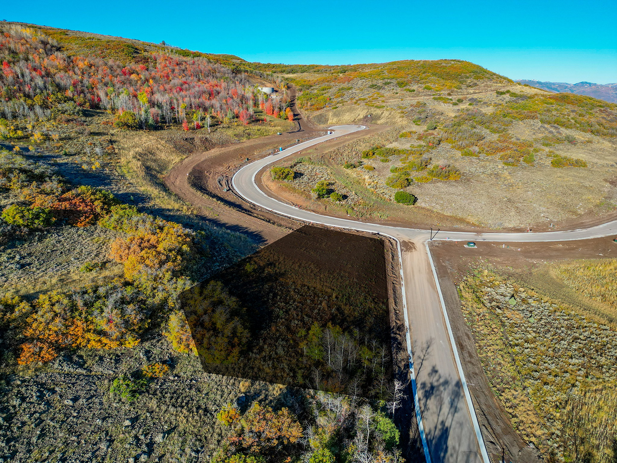 Expansive land parcel featuring established paved road frontage and a natural, varied topography