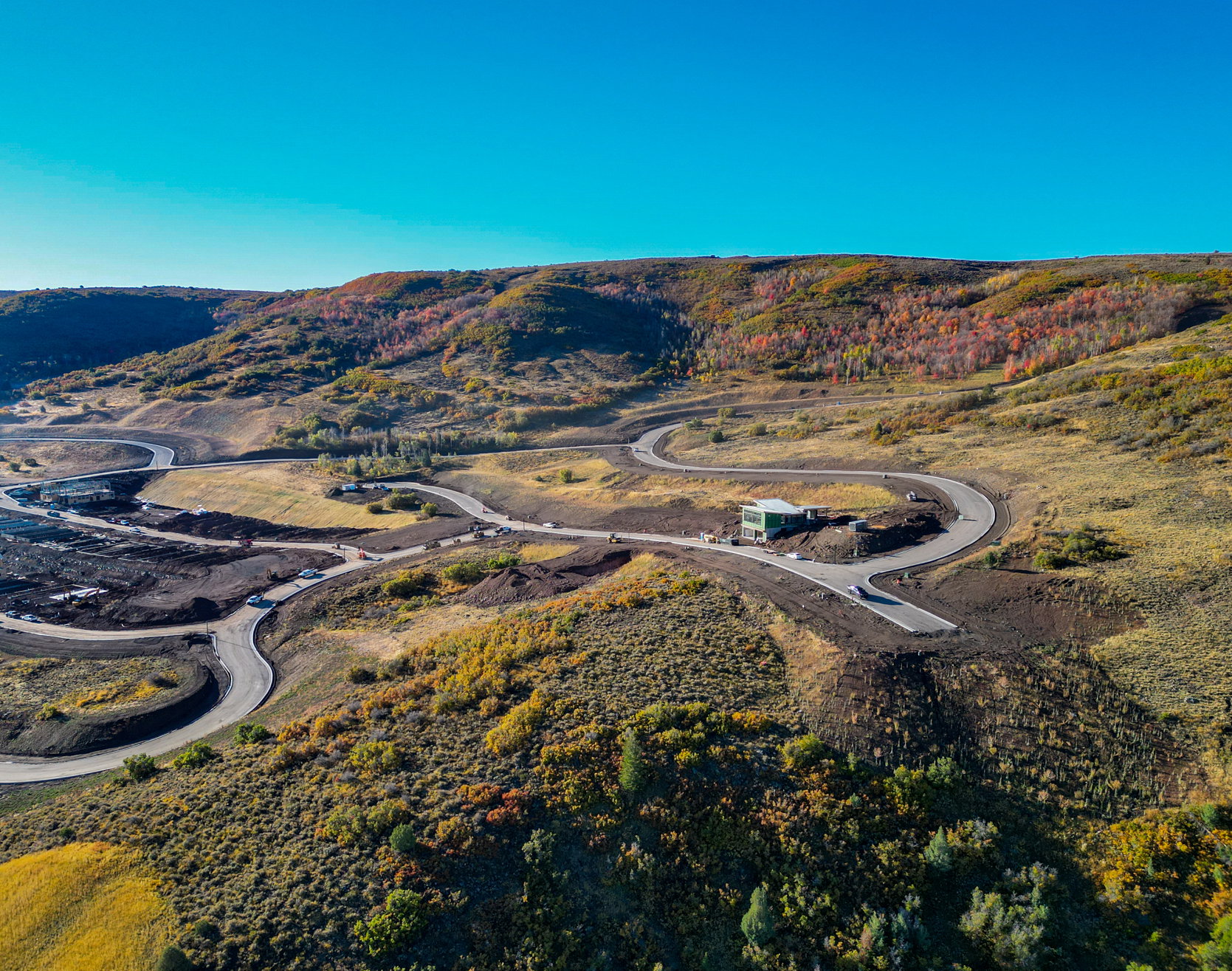 Expansive mountain landscape featuring winding roads and a contemporary structure
