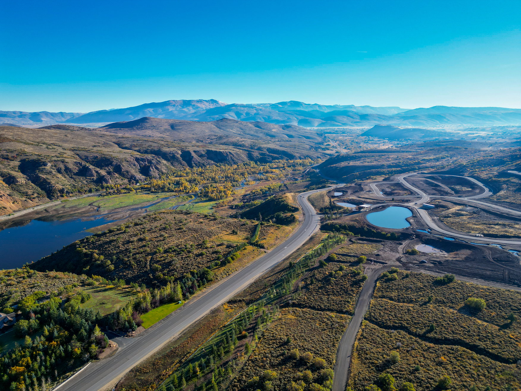 Expansive mountain landscape featuring paved roads and a tranquil lake