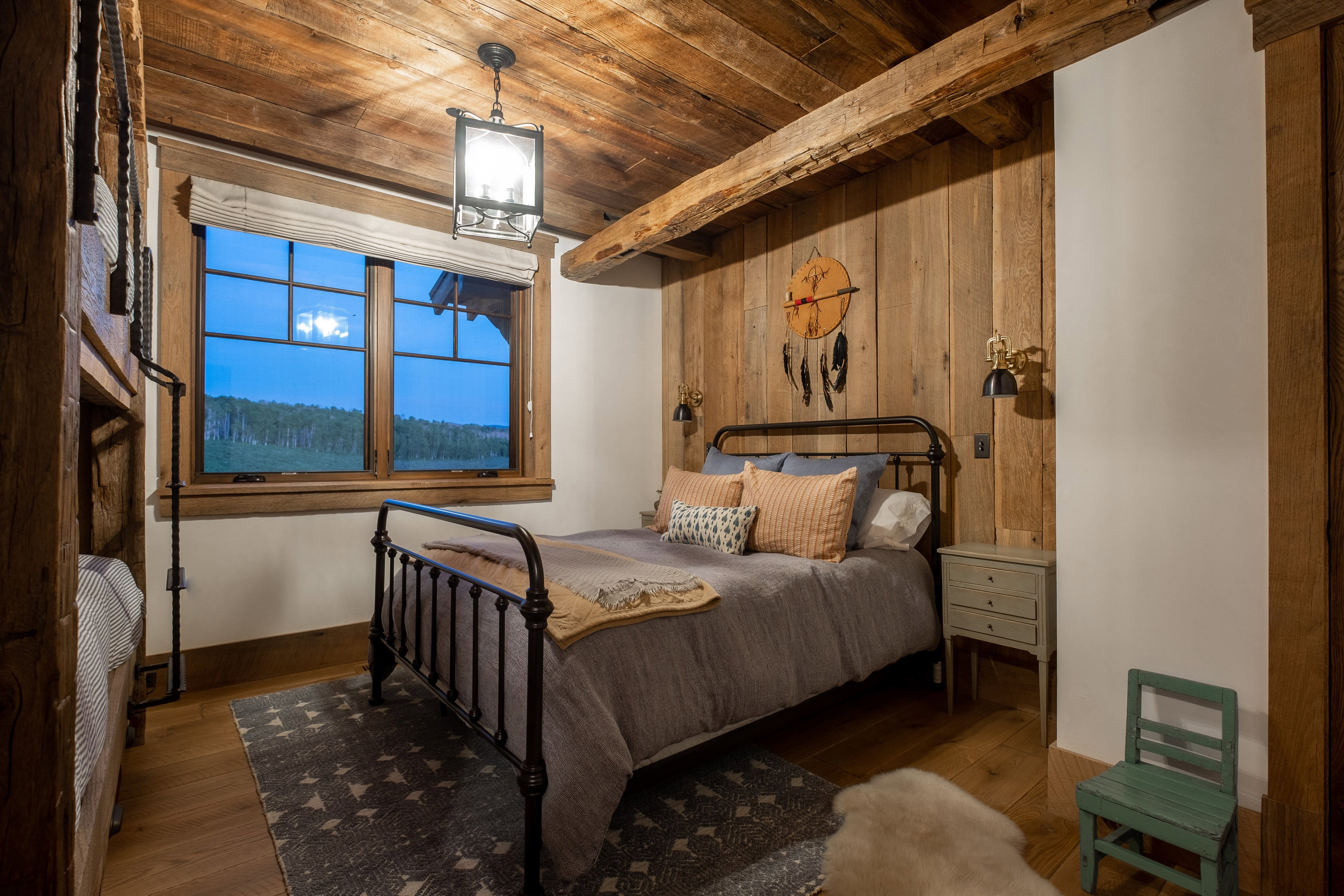 Bedroom featuring wood-finish flooring, wood-paneled walls, exposed wood beam ceiling, and a large multi-pane window
