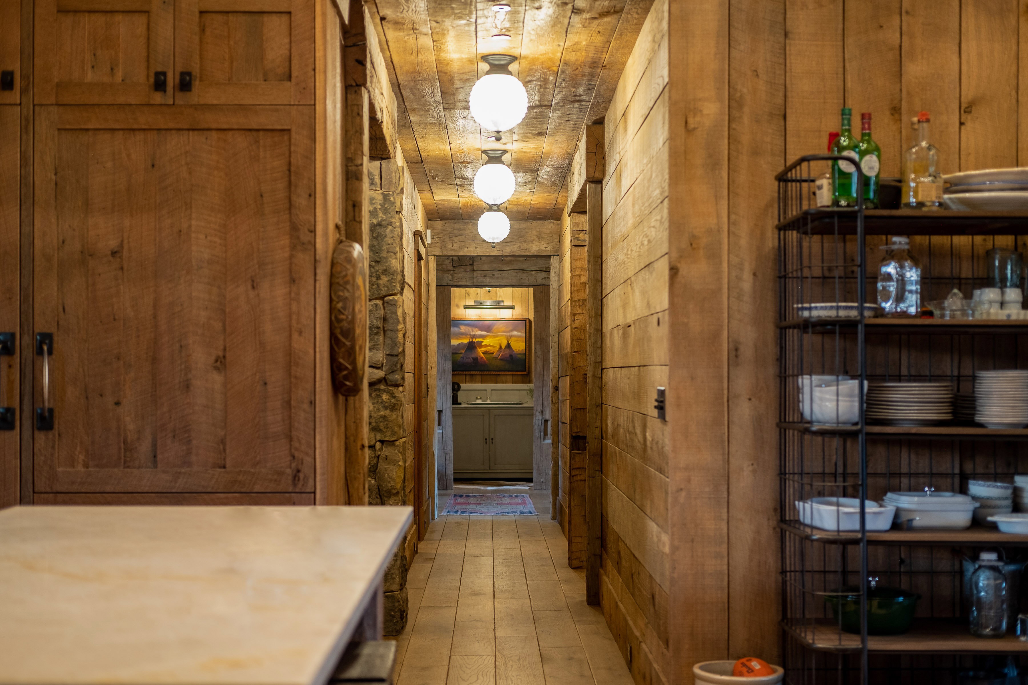 Rustic-style kitchen with natural wood paneling and cabinetry, featuring industrial-inspired spherical ceiling lights