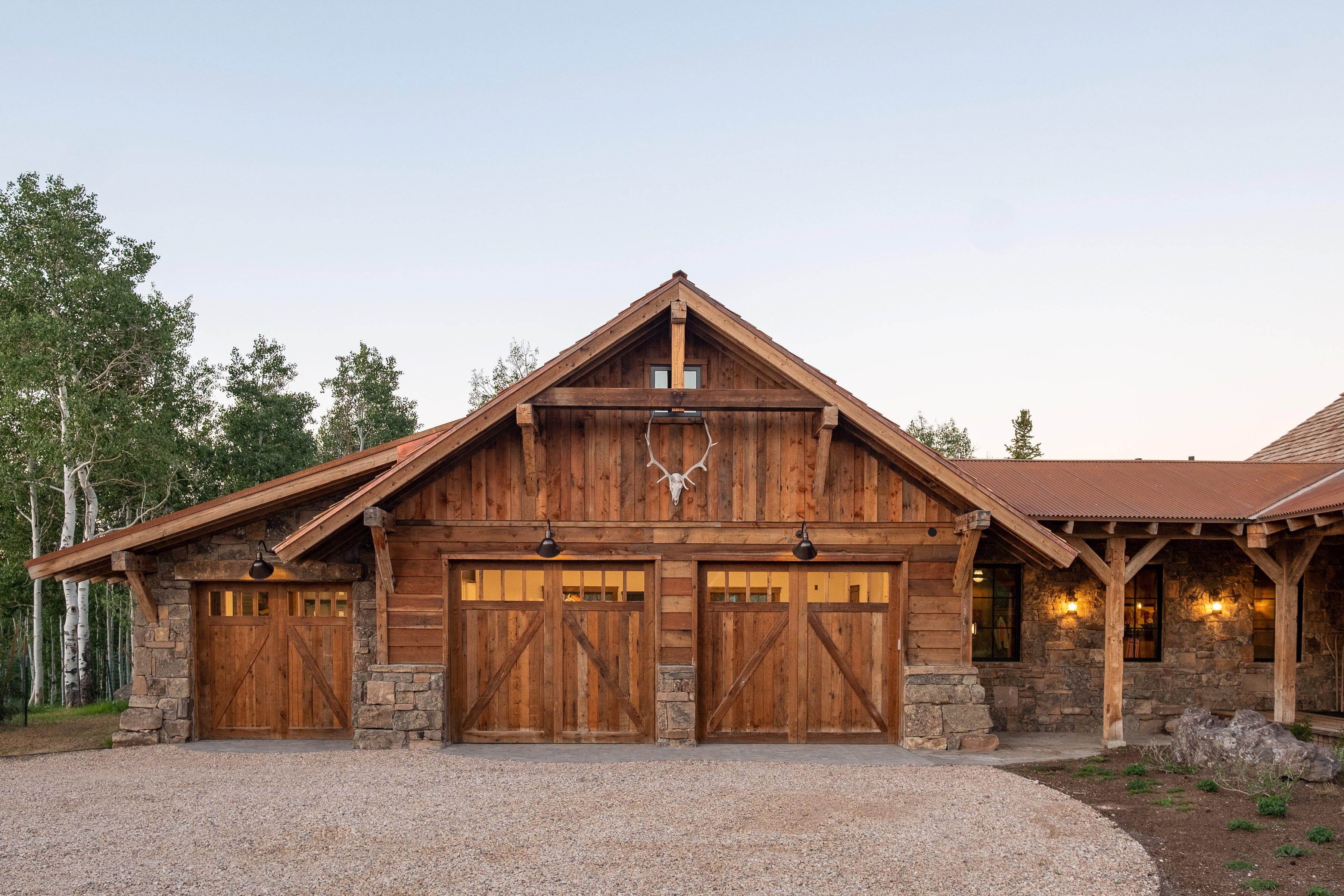 Rustic architectural style featuring a three-car garage with wood-paneled doors and stone accents