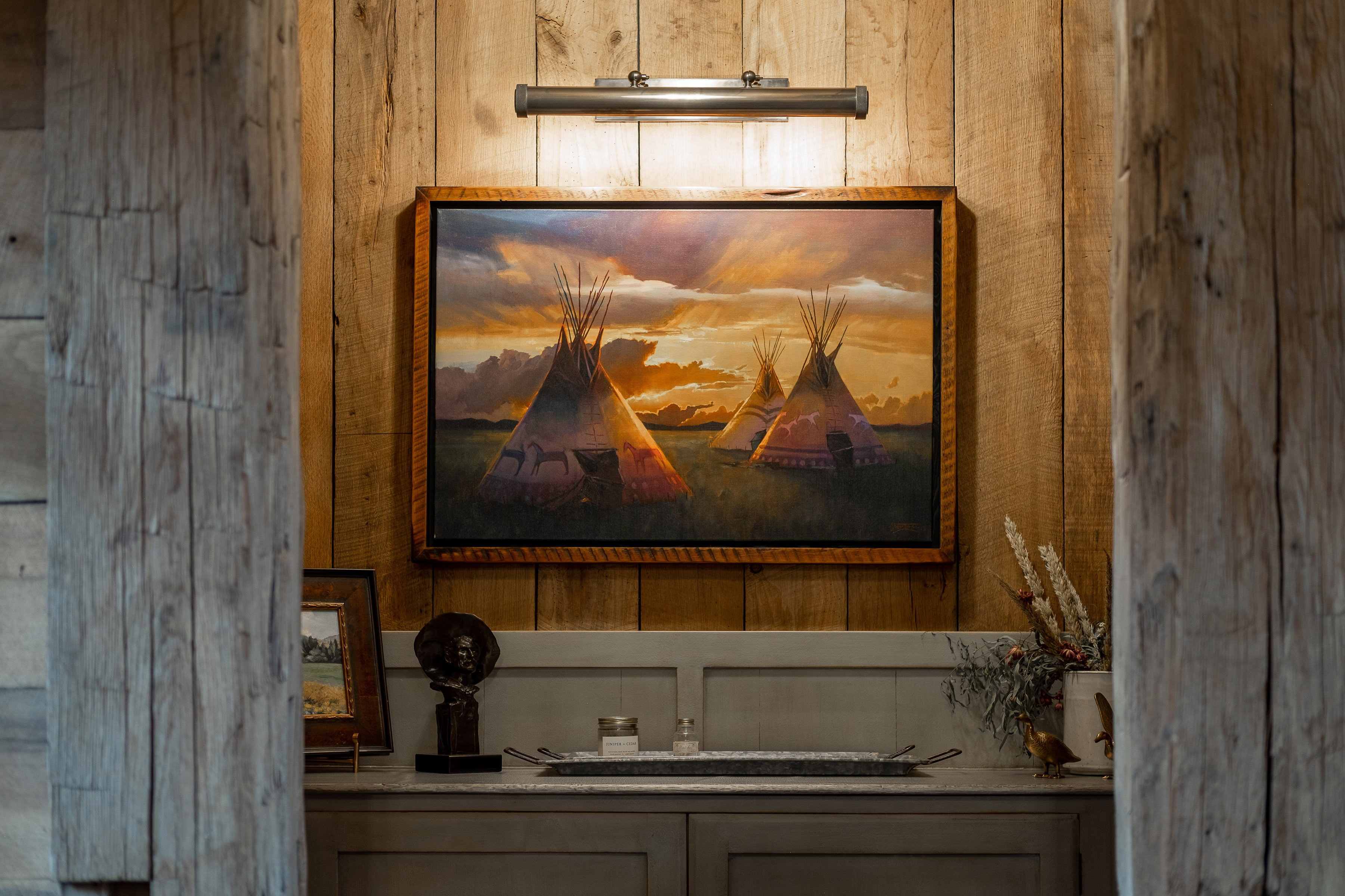 Wood paneling accent wall featuring a picture light, custom cabinetry, and a stone countertop