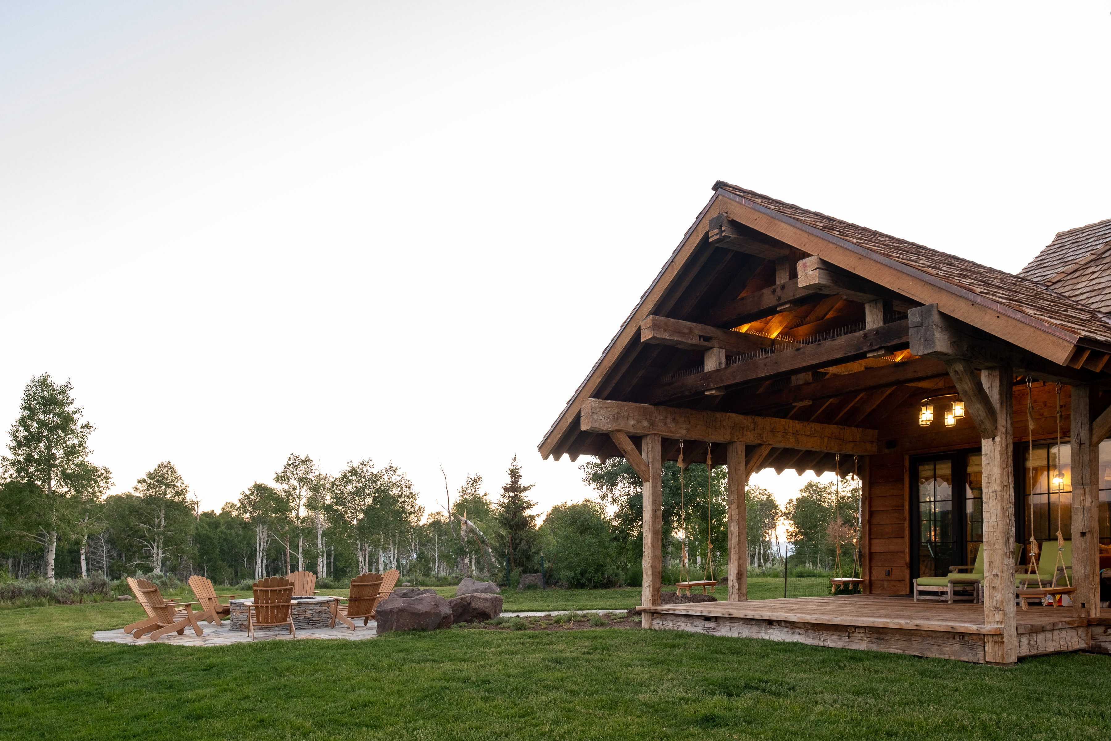 Expansive outdoor living area featuring a covered porch with exposed timber framing and a shingled roof