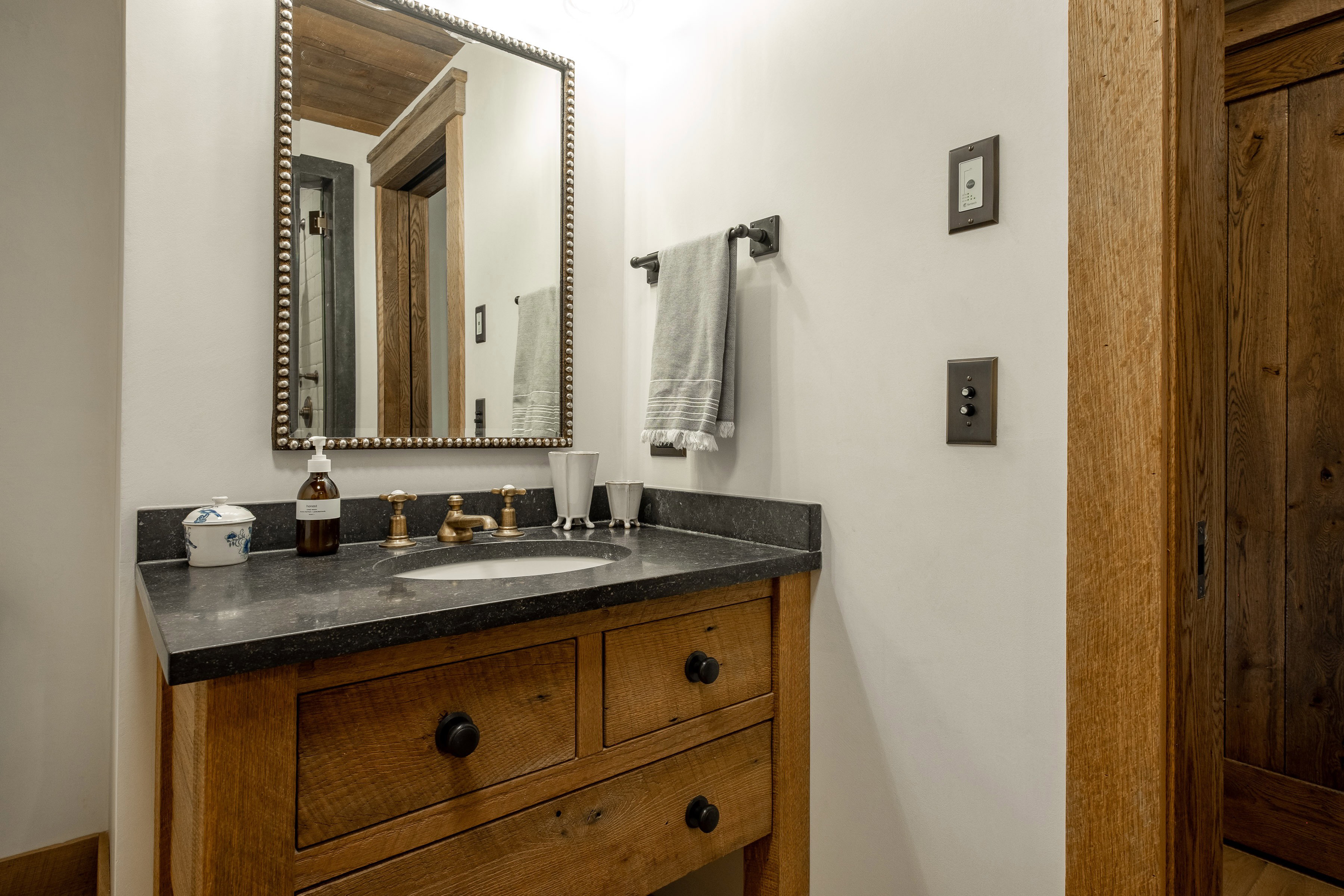 Custom wood-finish vanity featuring a dark countertop, an undermount sink, and a decorative mirror
