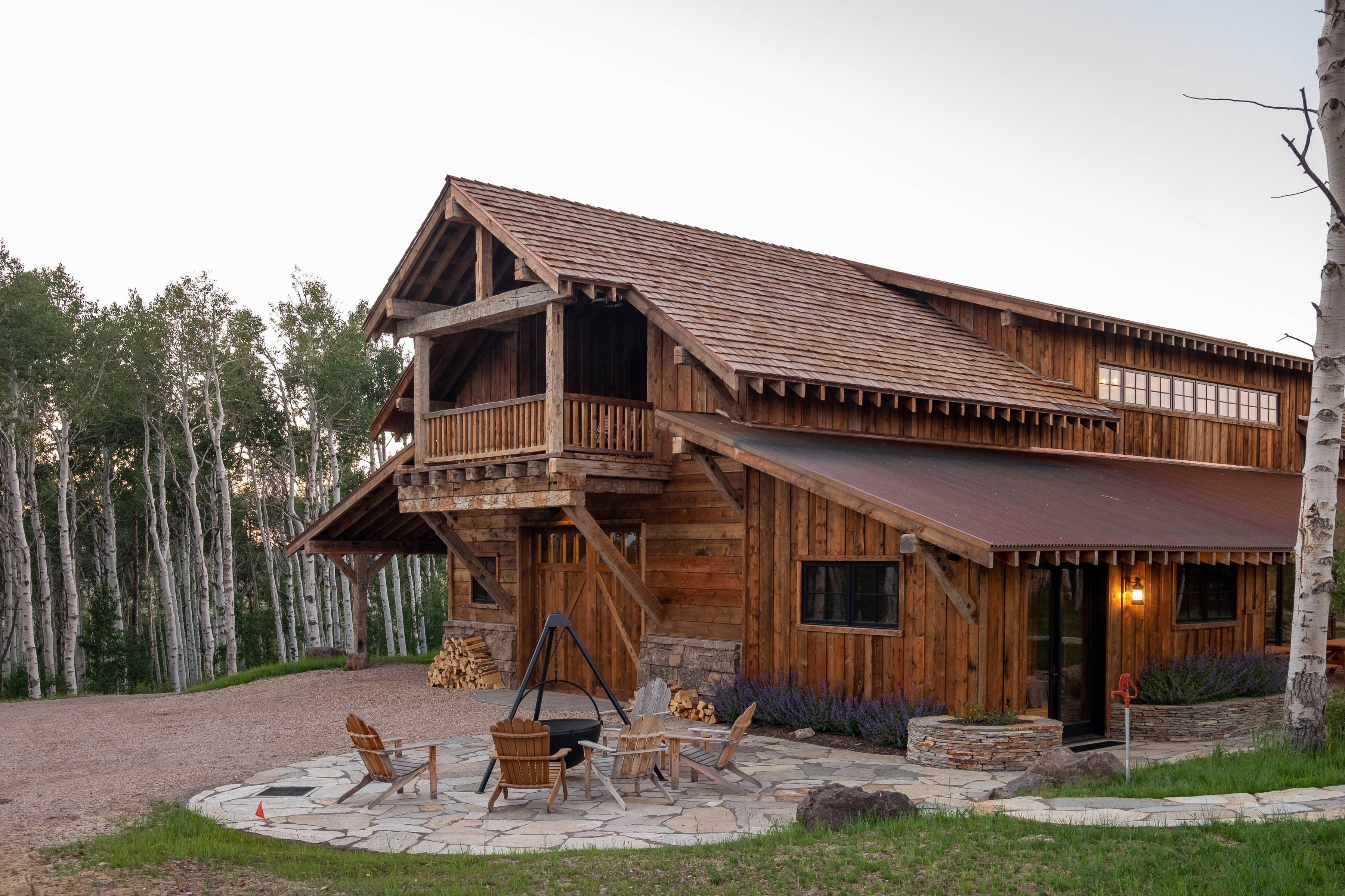 Rustic timber-frame construction featuring a natural wood-shingle roof and a covered metal roof extension