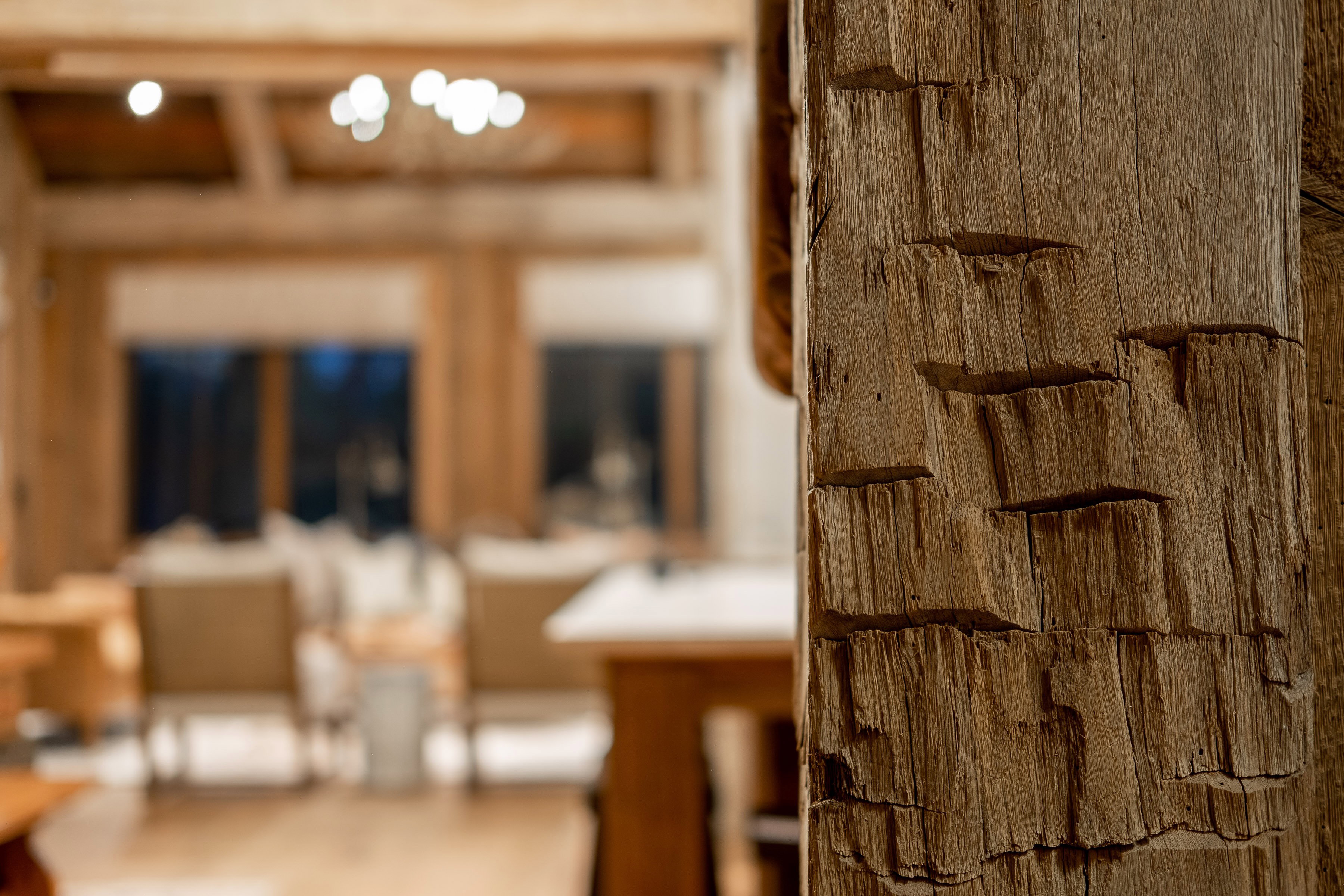 Textured wood column with visible grain detailing, complemented by a coffered ceiling and built-in lighting in the background