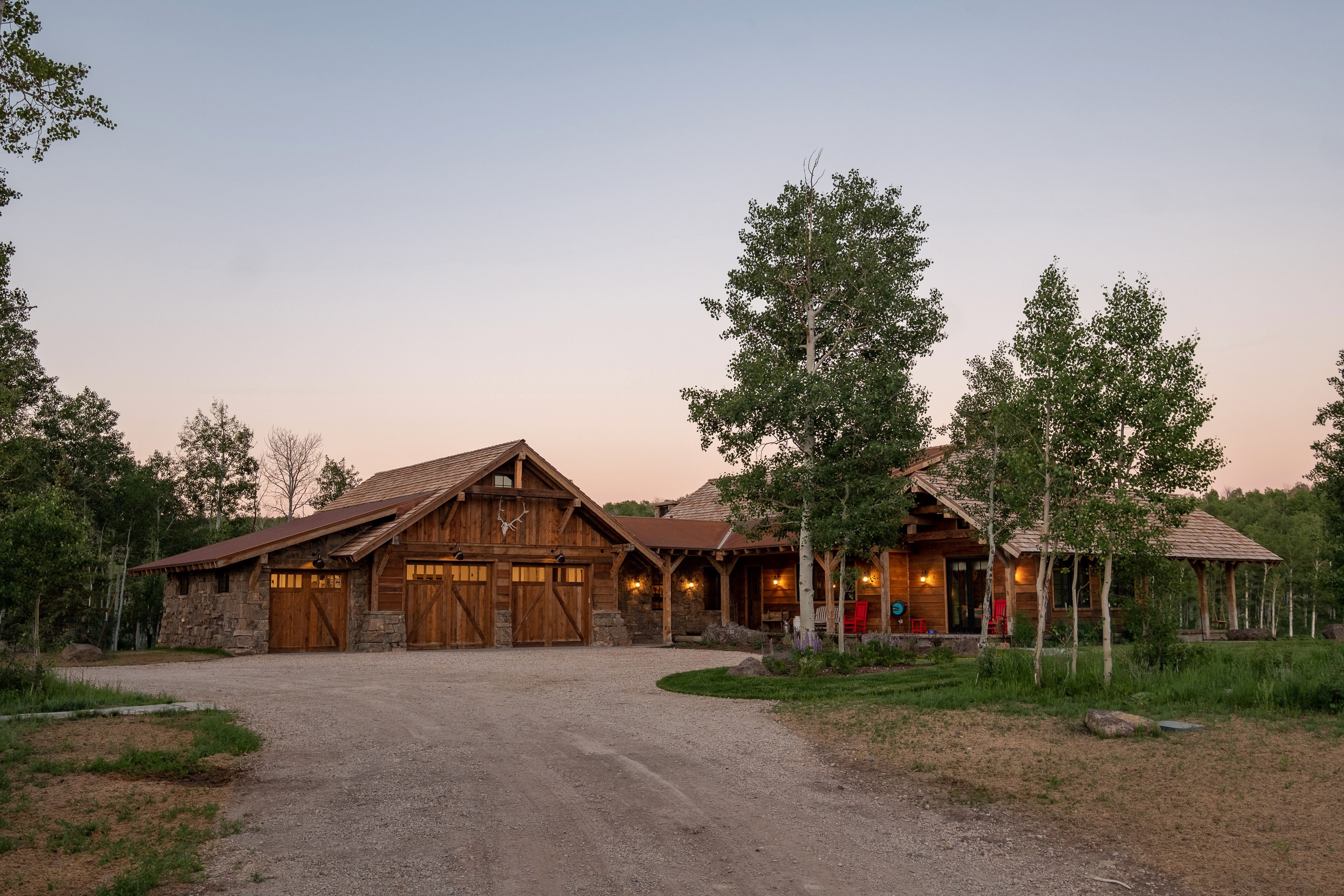 Rustic-style exterior featuring extensive wood siding, stone accents, and a multi-car garage with wood doors