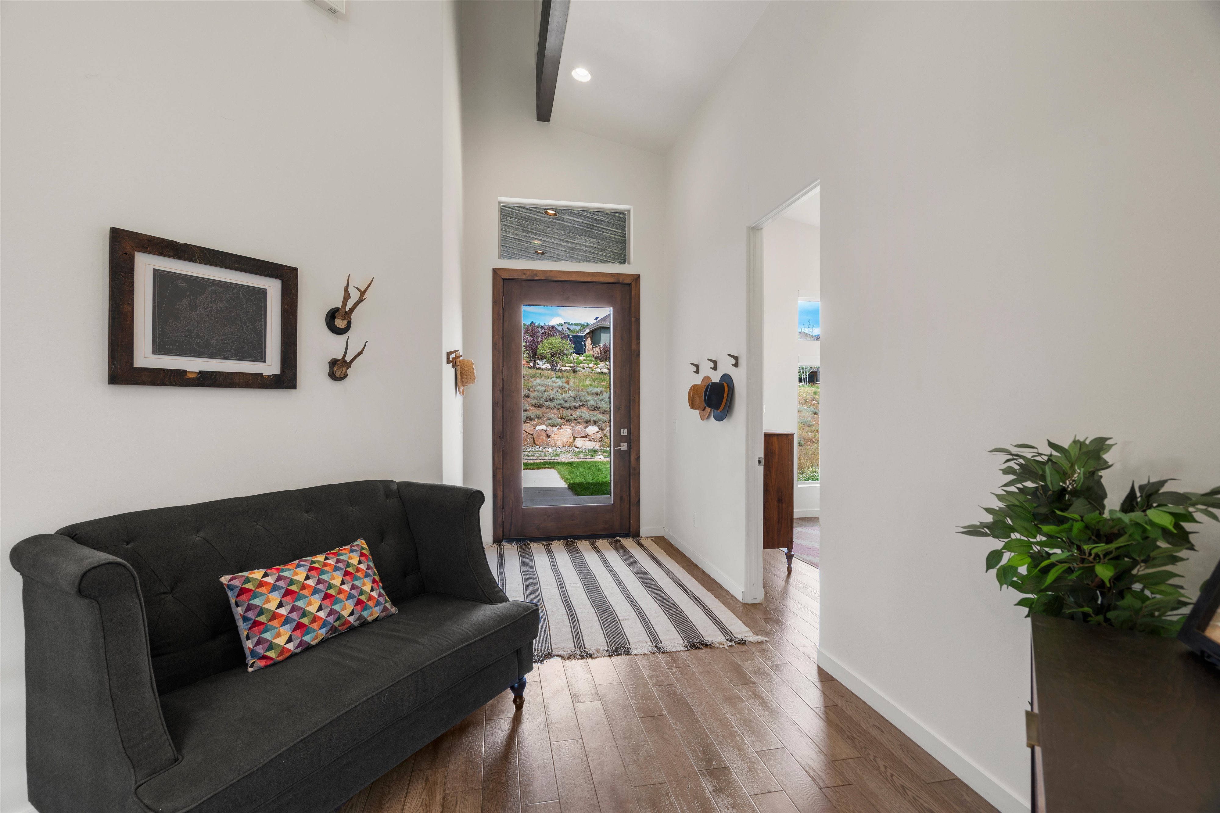 Entryway featuring wood-finish flooring, a full-lite door with transom window, and high ceilings with exposed beams