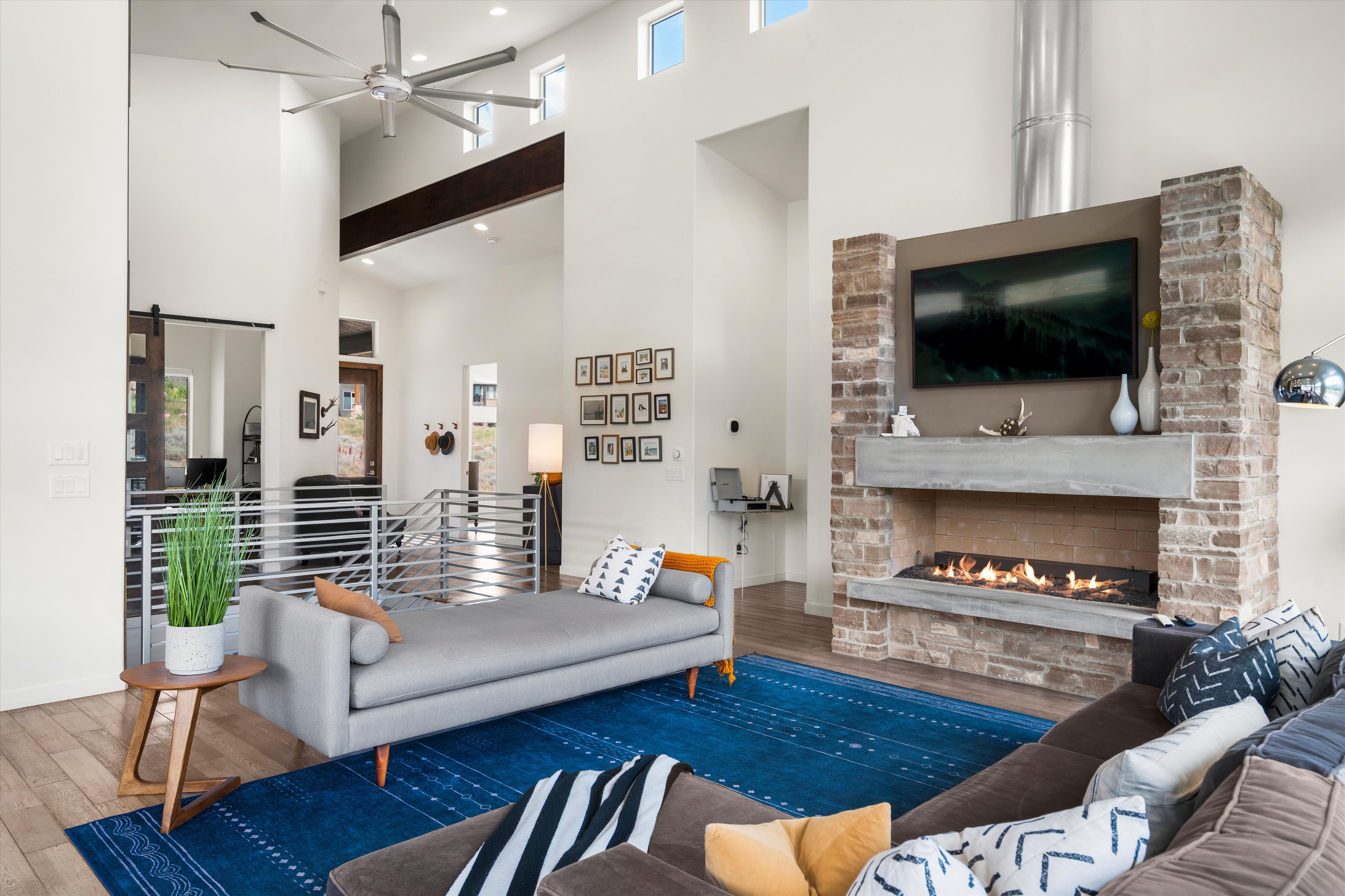 Two-story living area featuring a stone-clad fireplace with a concrete mantel