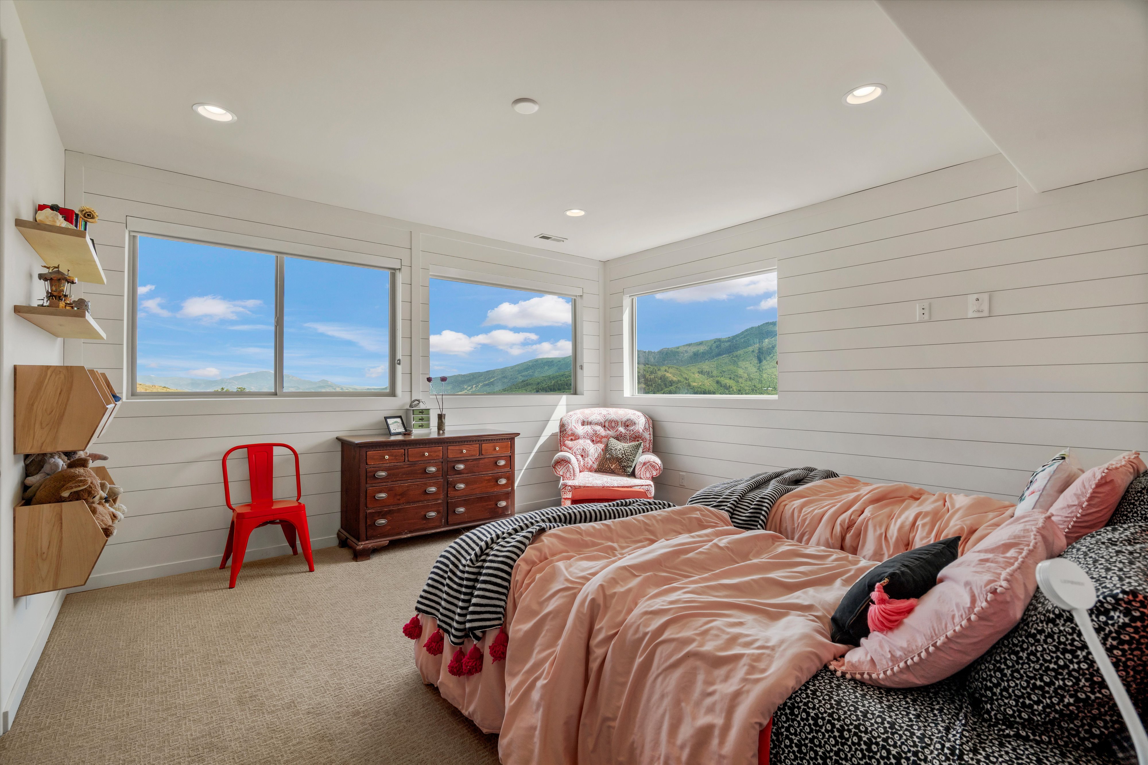 Carpeted room featuring horizontal shiplap walls, recessed ceiling lighting, and multiple windows showcasing a mountainous landscape
