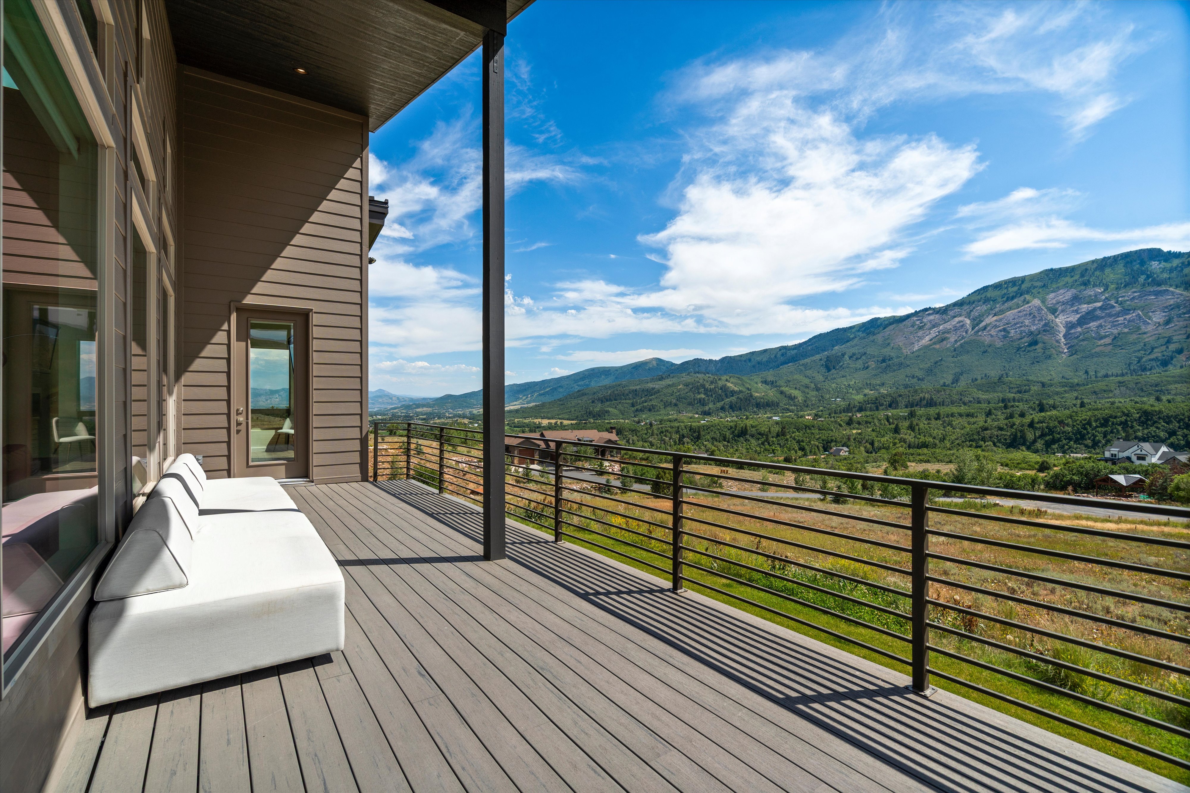 Spacious elevated deck featuring composite decking, horizontal metal railings, and a direct mountain backdrop
