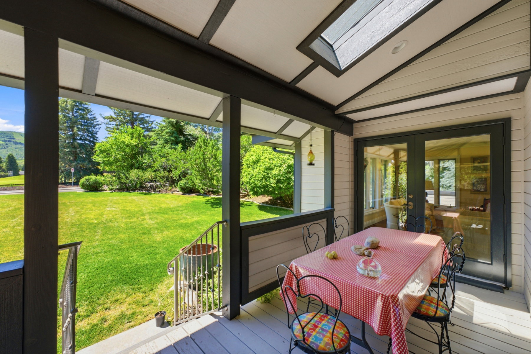 Covered porch featuring a skylight, painted wood-finish flooring, and direct access to an expansive lawn