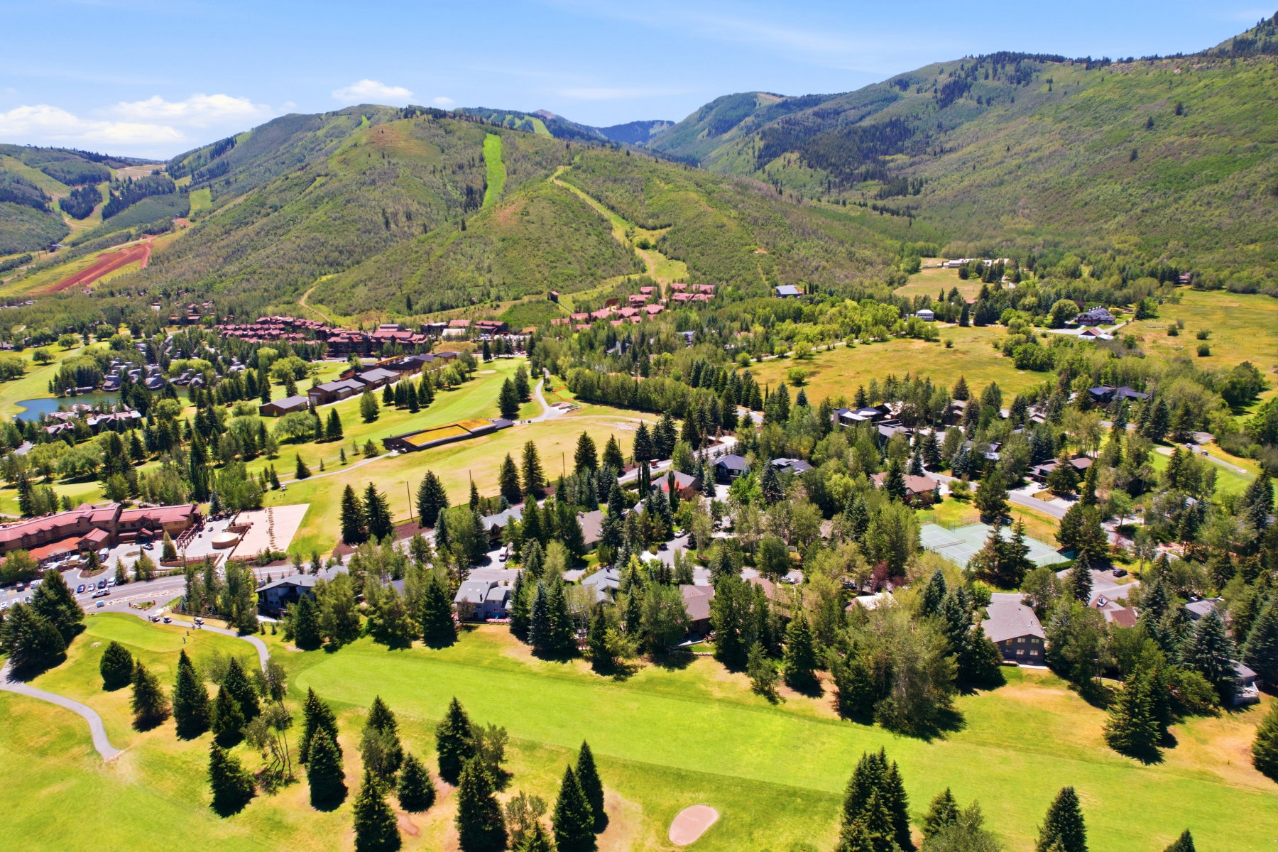 Expansive mountain landscape featuring a golf course, residential properties, mature trees, and natural terrain