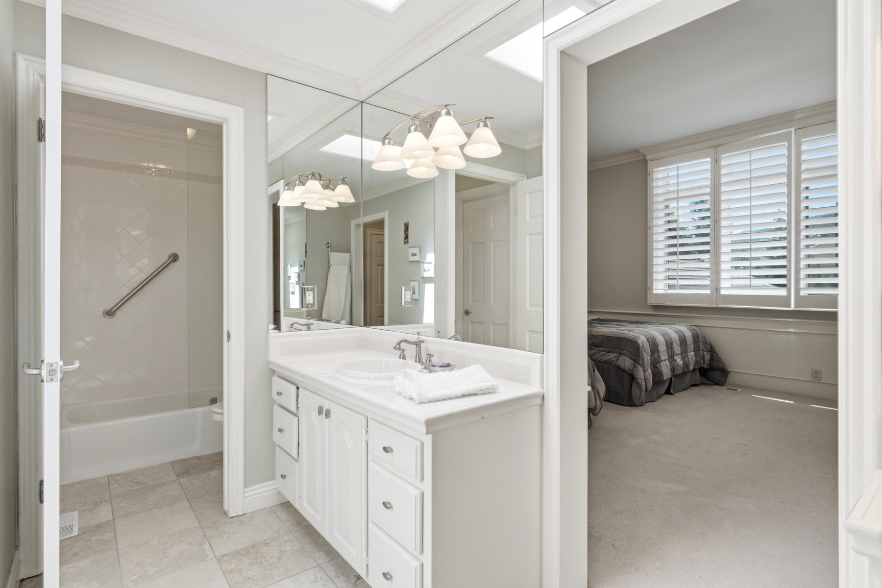 Bathroom featuring a white vanity with dual sinks and a large mirrored wall
