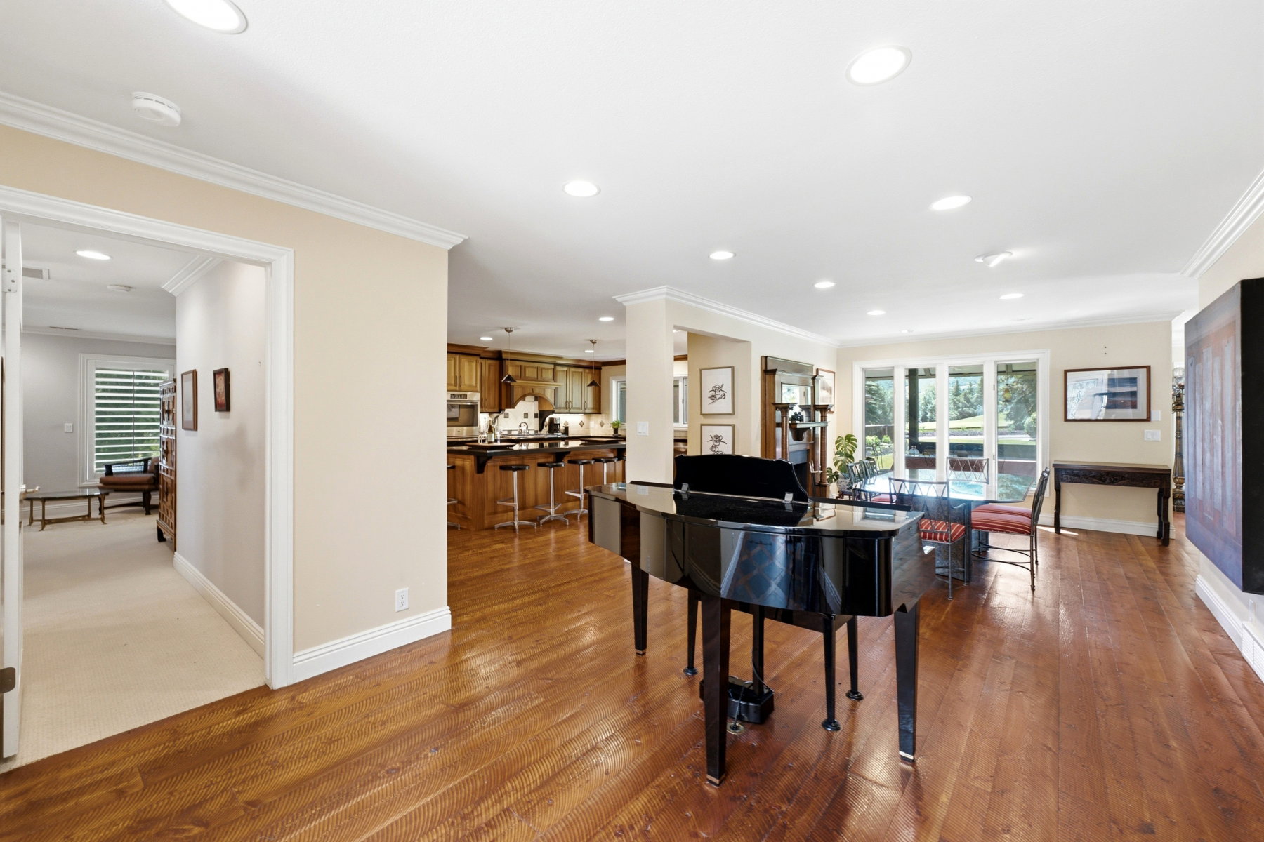 Open-concept living area featuring rich wood-finish flooring, recessed lighting, and crown molding