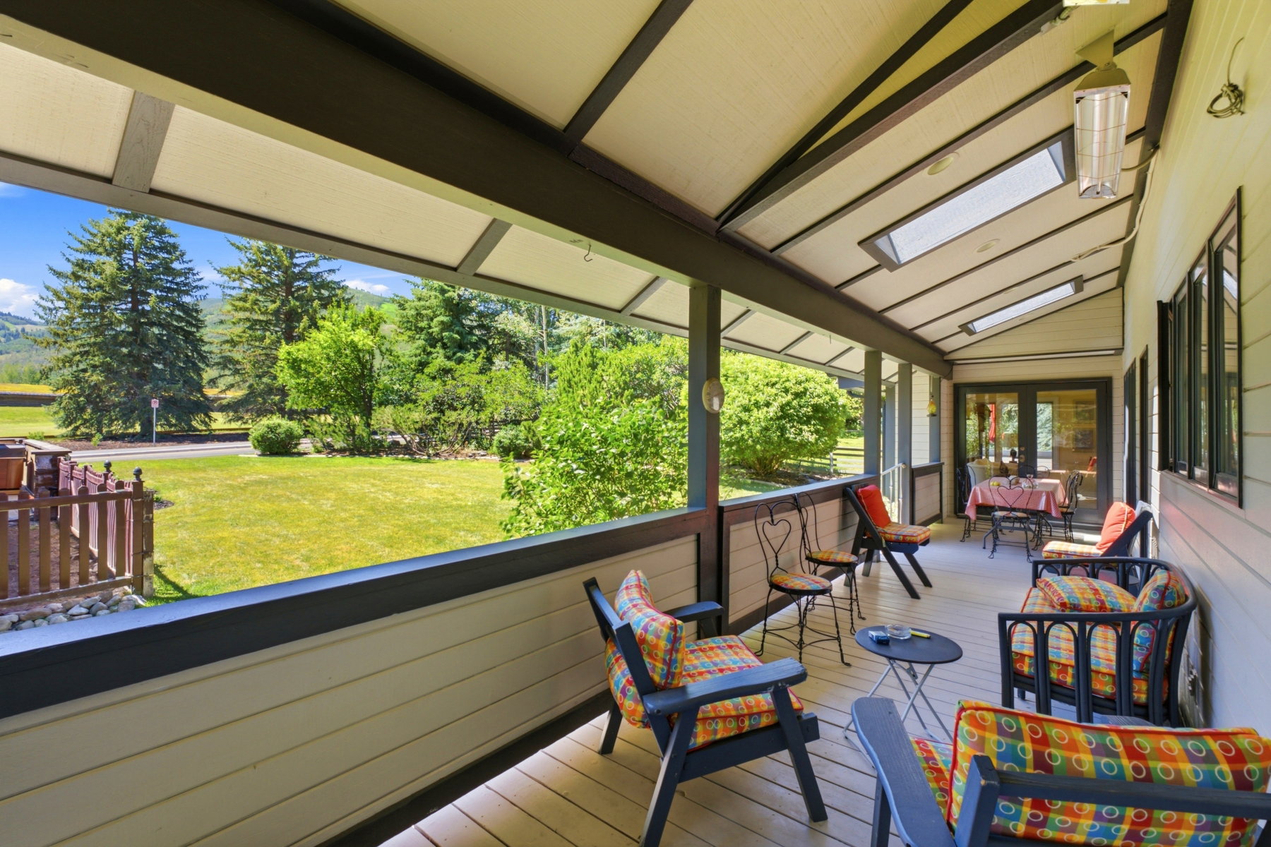 Covered porch featuring wood-finish flooring, a vaulted ceiling with skylights, and multiple windows