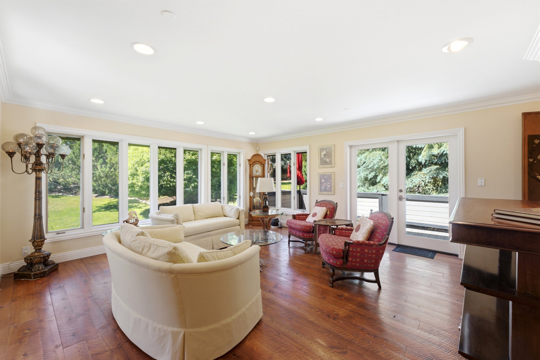 Living area featuring wood-finish flooring, recessed lighting, expansive windows, and glass-paneled double doors opening to an exterior space