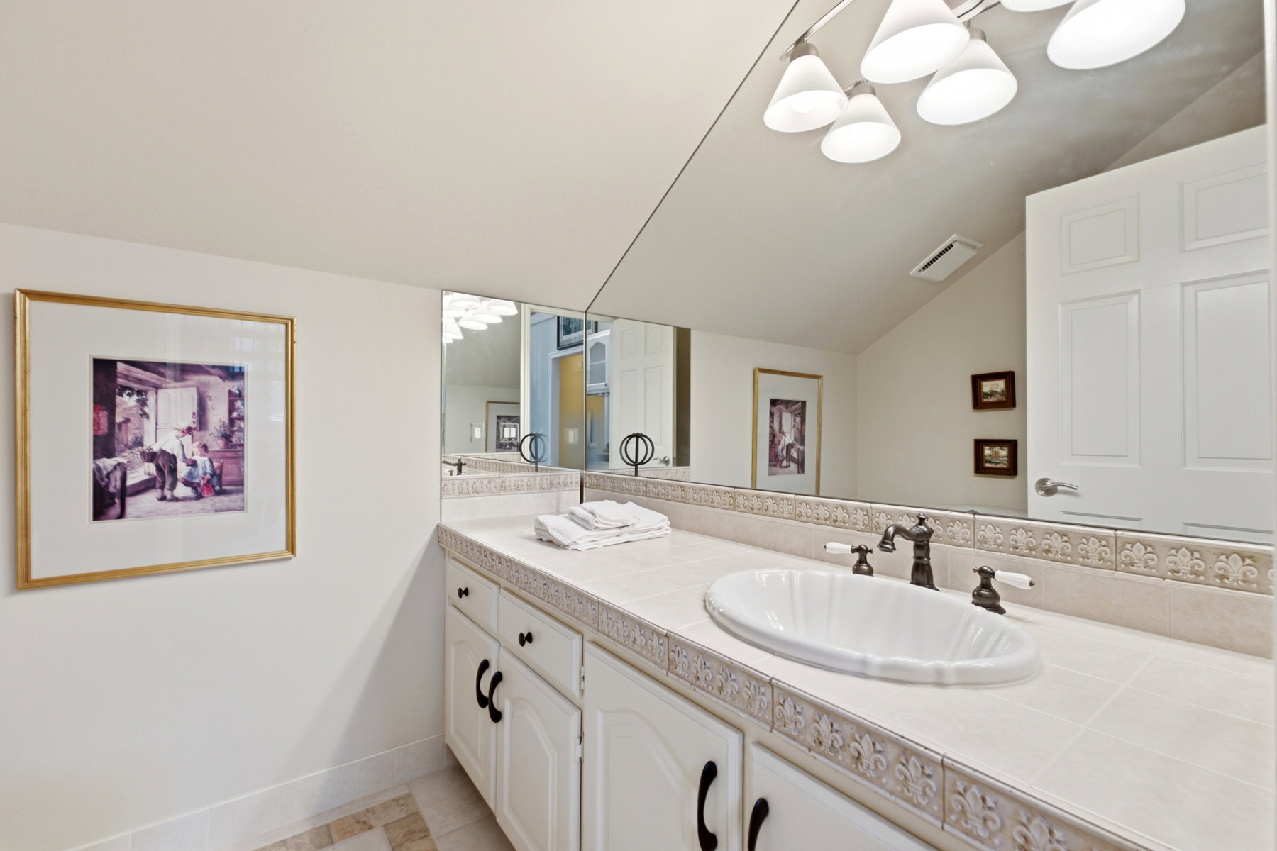 Bathroom vanity featuring an integrated sink, tile countertop, and full-wall mirror