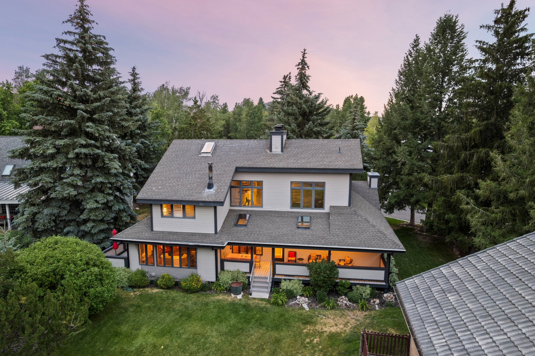 Modern residential architecture featuring a light-colored facade with dark trim, prominent gables, and multiple skylights