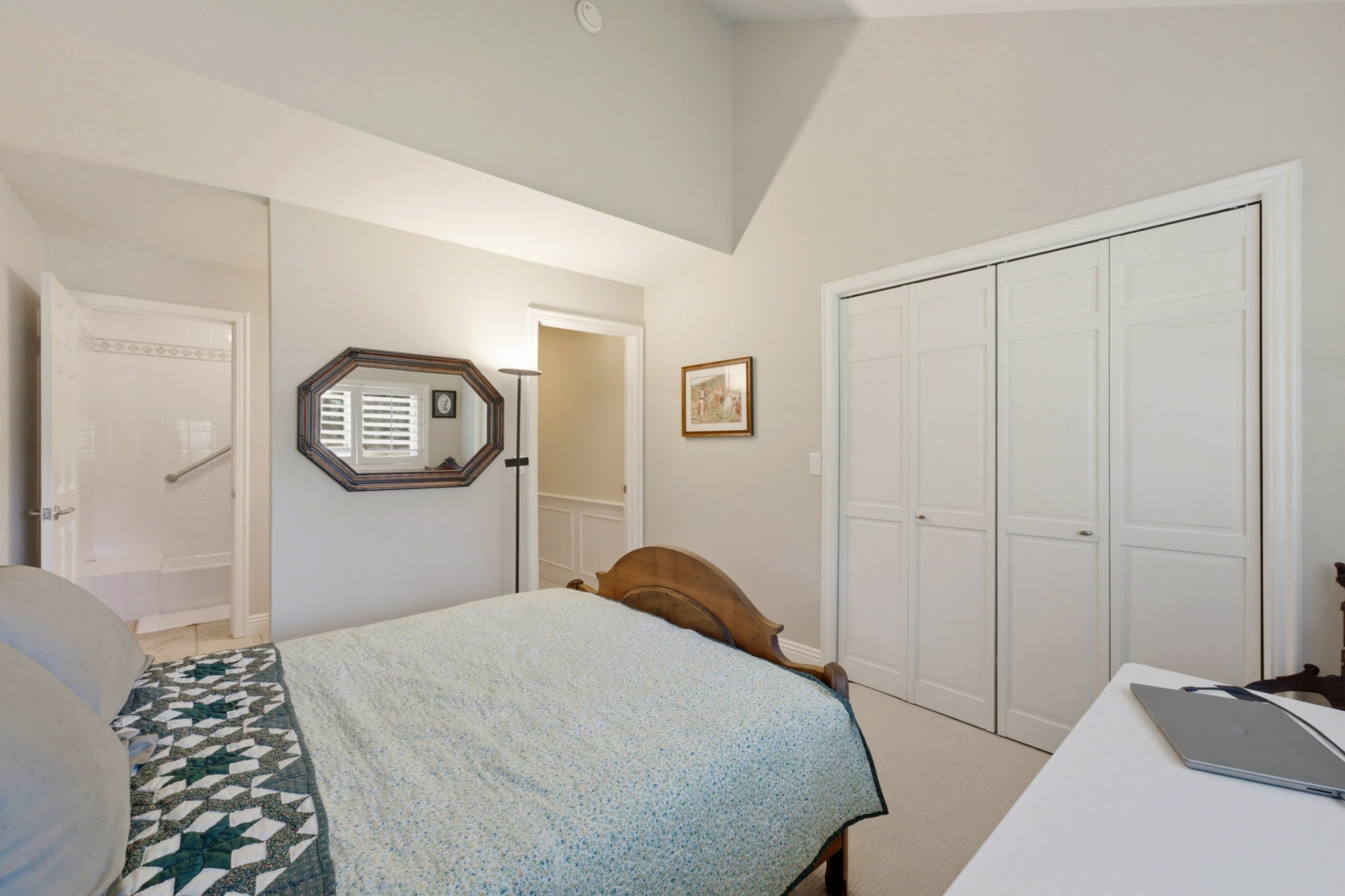 Vaulted ceiling bedroom with neutral wall tones and carpeted flooring