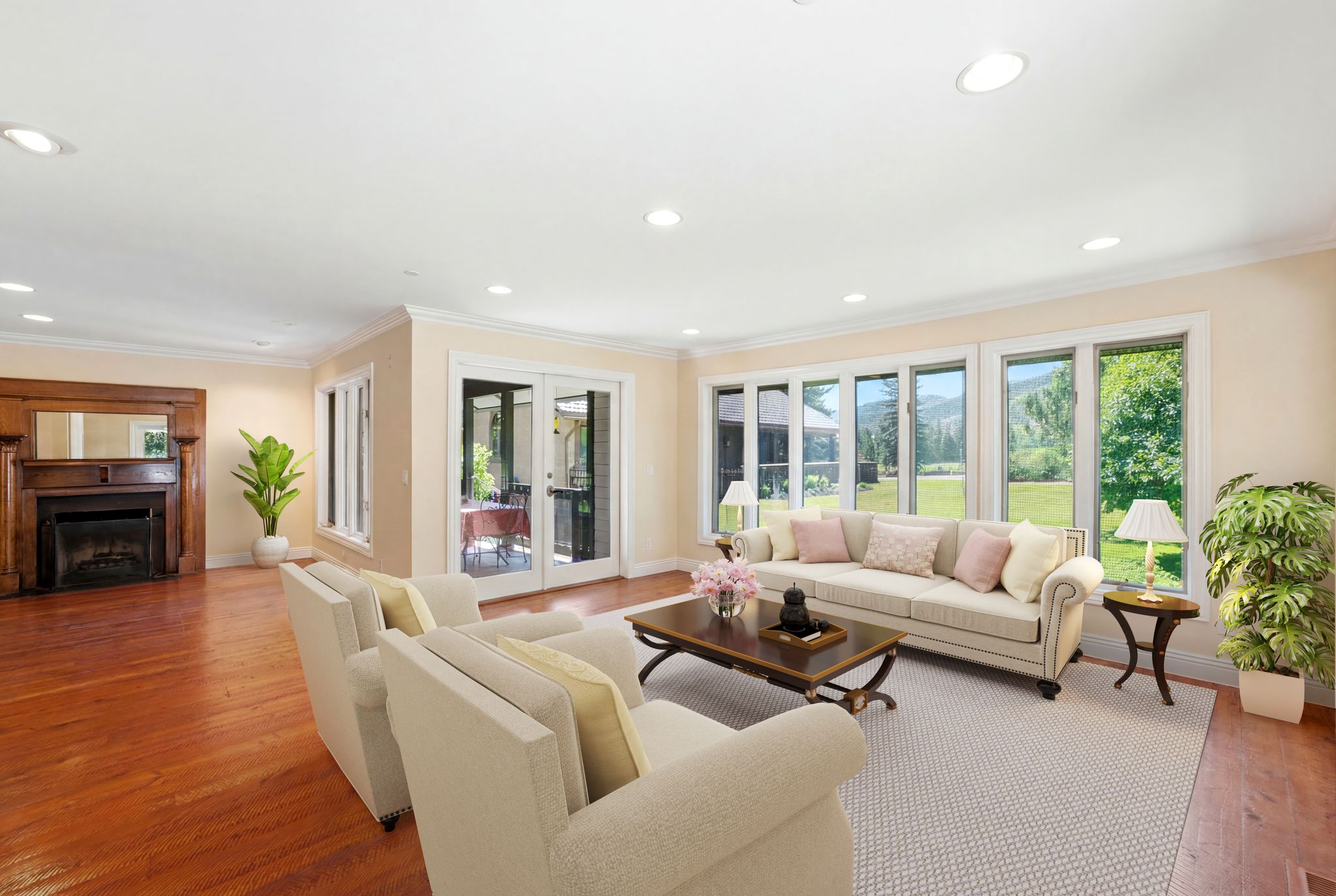 STAGED PHOTO-Spacious interior featuring hardwood flooring, recessed lighting, a decorative fireplace with a wood mantel, and multiple large windows - staged living room