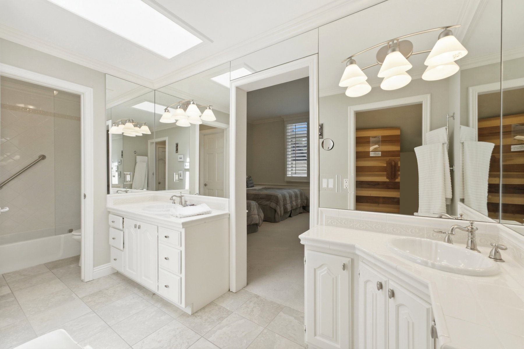 Spacious bathroom featuring dual white vanities, each with an integrated sink and brushed nickel faucet fixtures