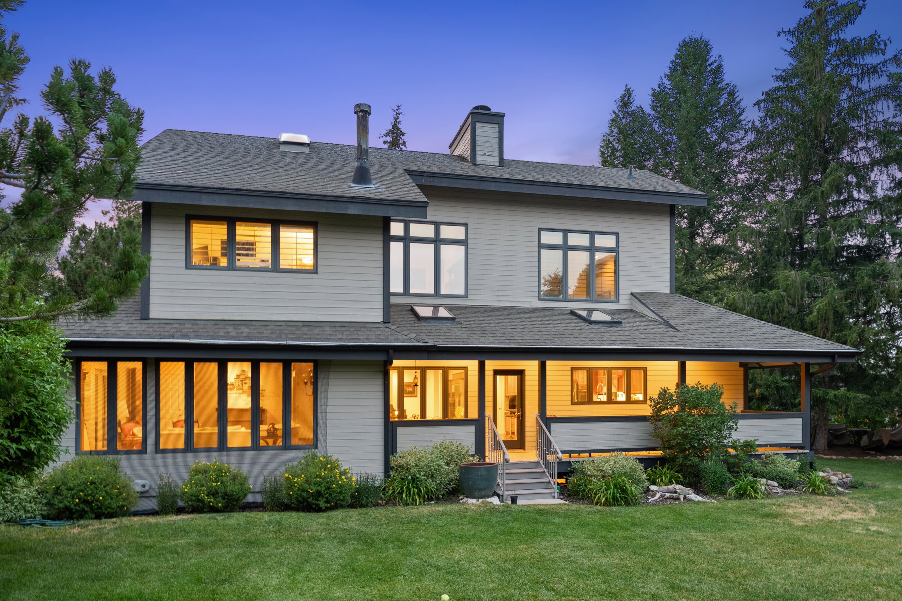 Two-story contemporary residence featuring a covered porch, multiple skylights, and a prominent chimney