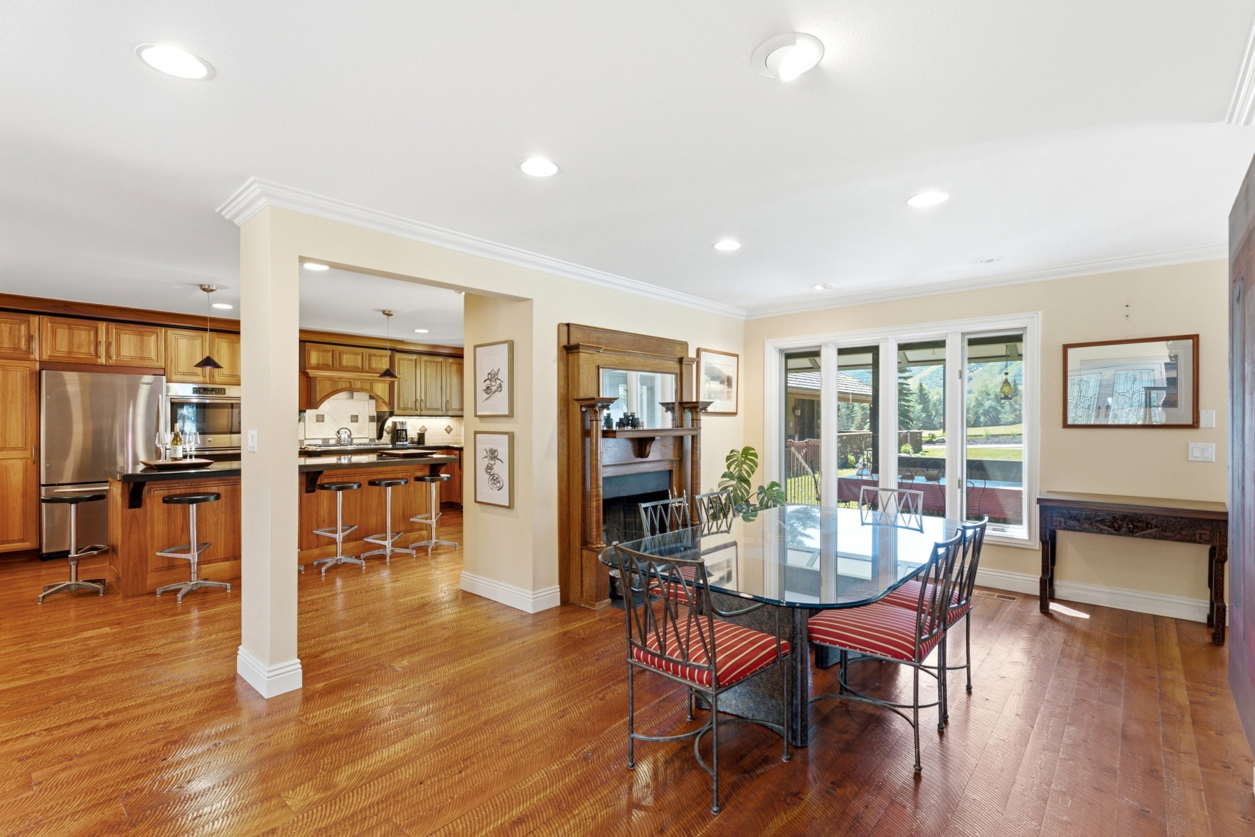 Open-concept dining area featuring wood-finish flooring, a decorative fireplace surround, and multiple windows
