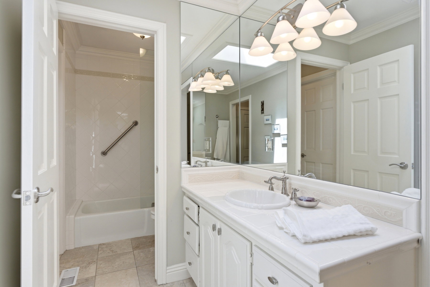 Bathroom featuring a white vanity with integrated dual sinks, extensive wall-mounted mirror, and a track light fixture