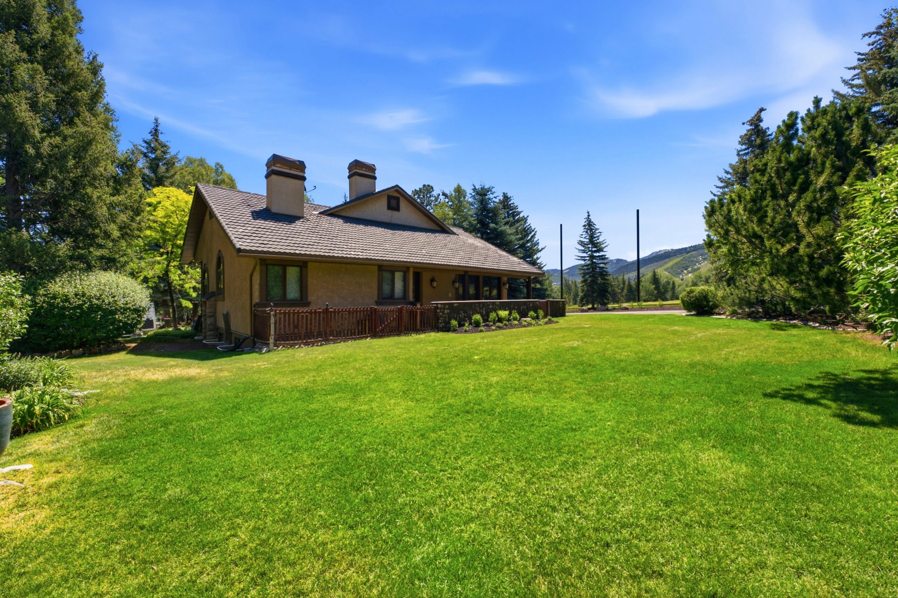 Spacious lawn extending from a stucco-finished residence with a shingle roof