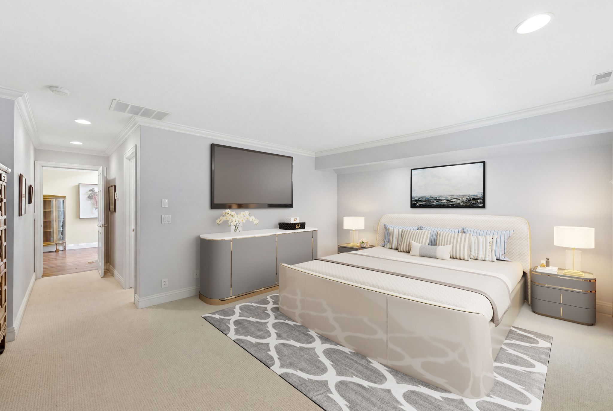 STAGED PHOTO-Recessed lighting illuminating a spacious room with crown molding, light-toned carpeting, and a hallway featuring wood-finish flooring - staged primary suite