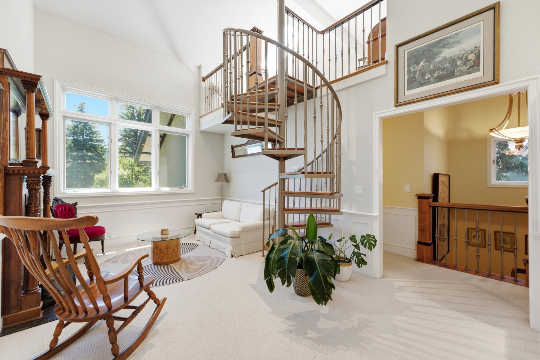Soaring ceilings with a grand spiral staircase featuring wood treads and metal balusters