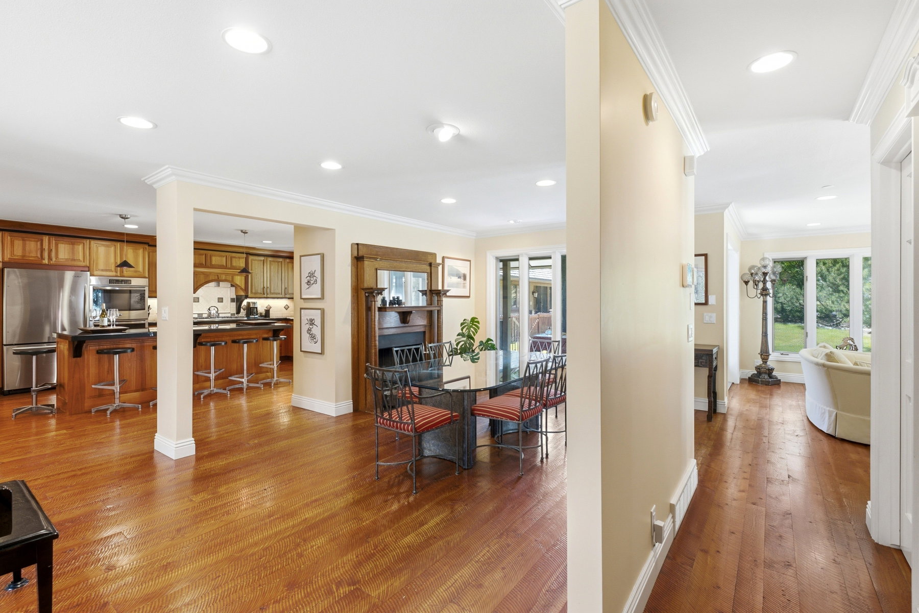 Open-concept living area featuring rich wood-finish flooring, recessed lighting, and crown molding