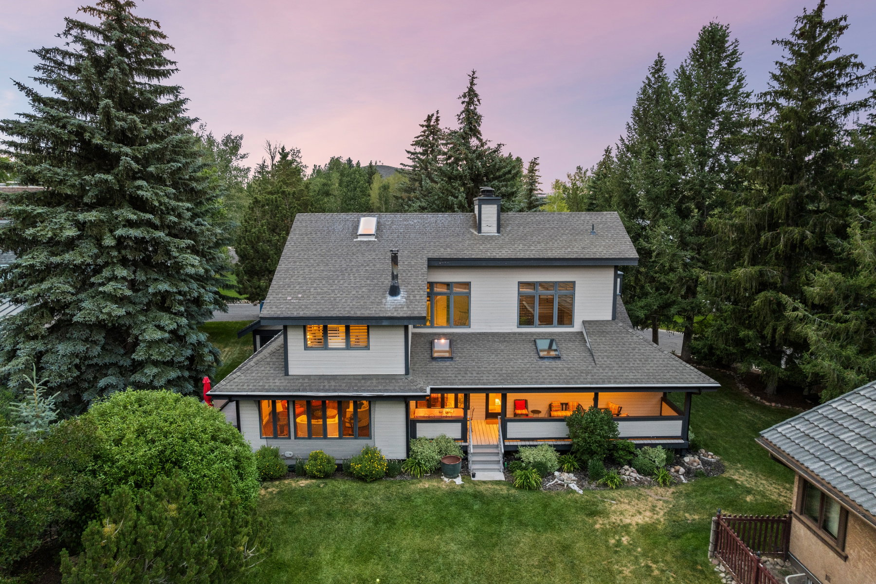 Multi-level exterior featuring a covered porch, abundant windows, and a shingled roof with skylights
