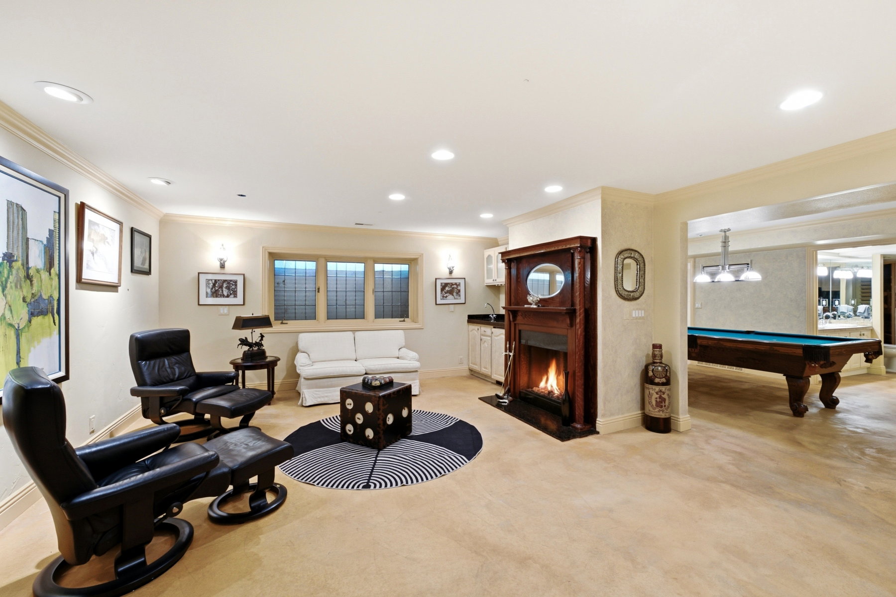 Spacious recreation area featuring a wood-mantel fireplace, wet bar with white cabinetry, recessed lighting, and a separate billiards area