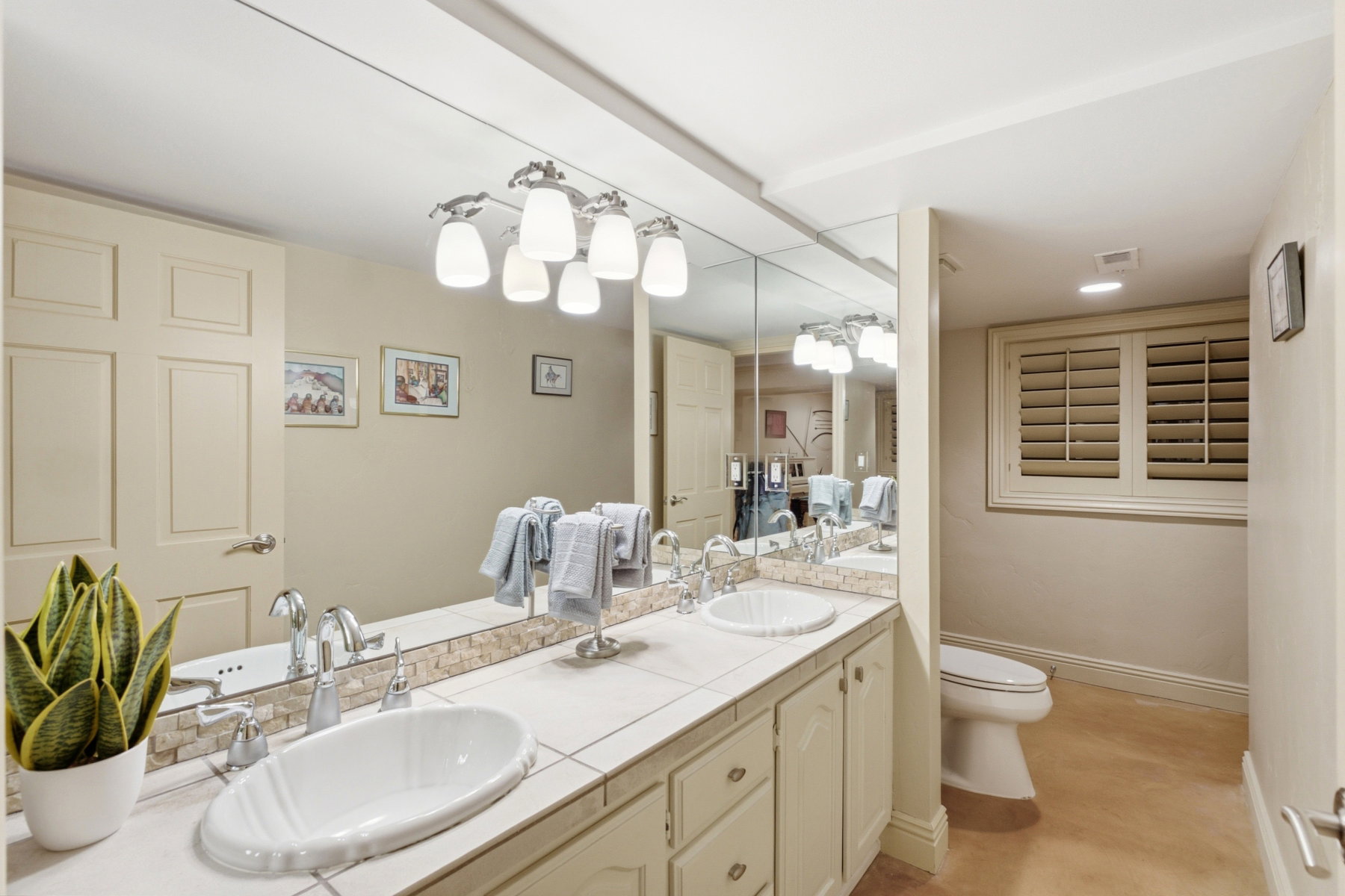 Double vanity featuring oval vessel sinks, chrome fixtures, and a tiled countertop