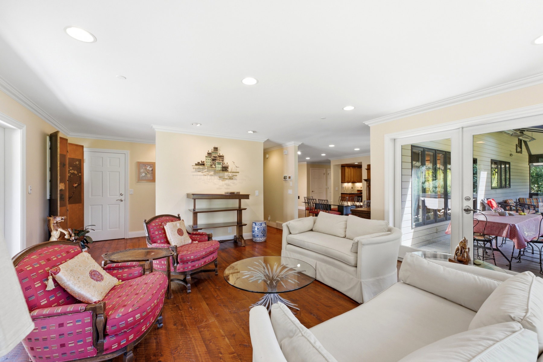 Living area featuring wood-finish flooring, recessed lighting, white crown molding, and sliding glass doors opening to an outdoor patio