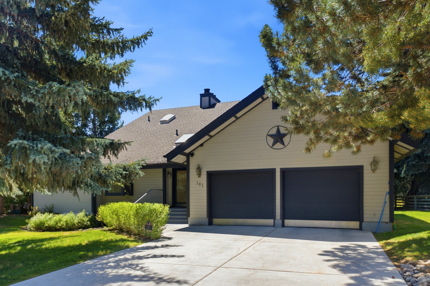 Contemporary residence featuring a two-car garage with dark paneled doors