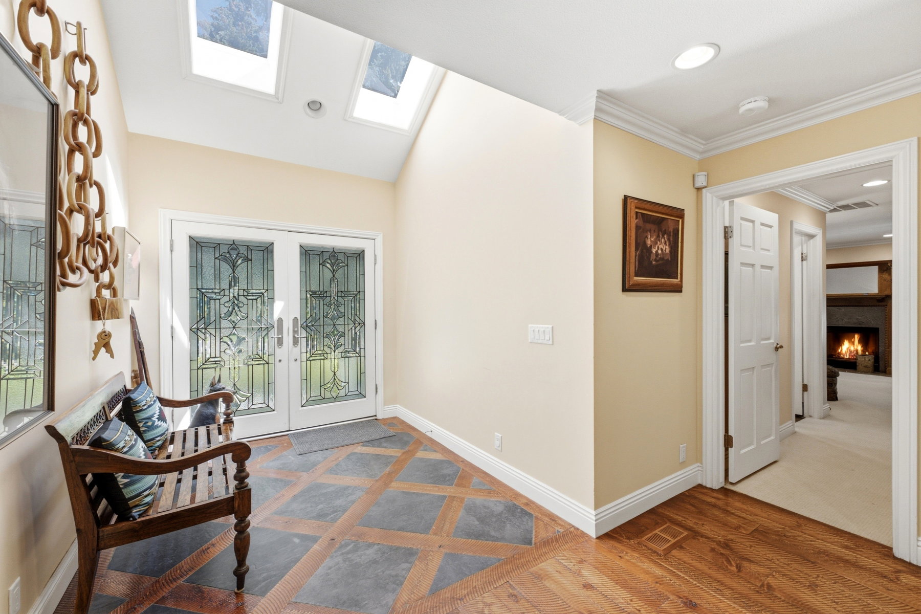 Foyer with a vaulted ceiling, dual skylights, and double entry doors featuring decorative glass