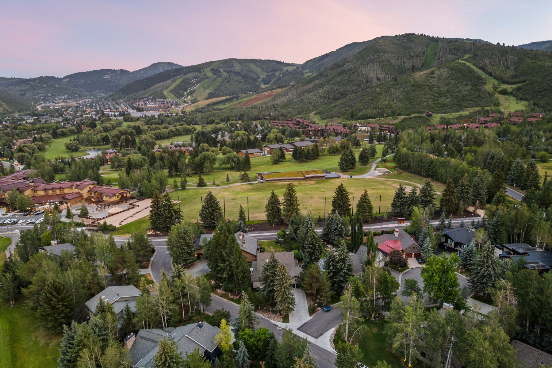 Aerial perspective of a mountain community featuring mature trees, residential properties with varied rooflines, and a golf course