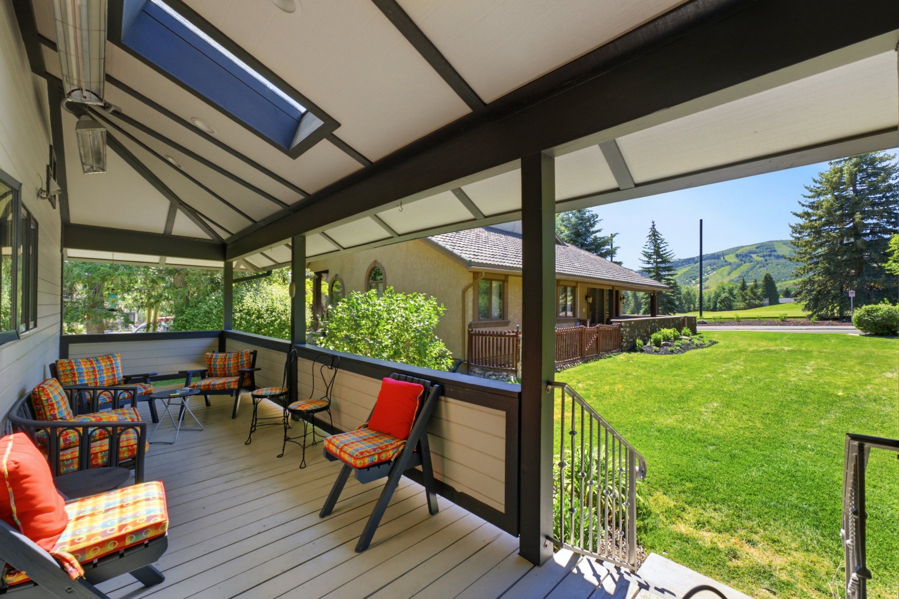 Covered outdoor porch featuring a skylight, exposed beam ceiling, painted wood-finish decking, and metal railings