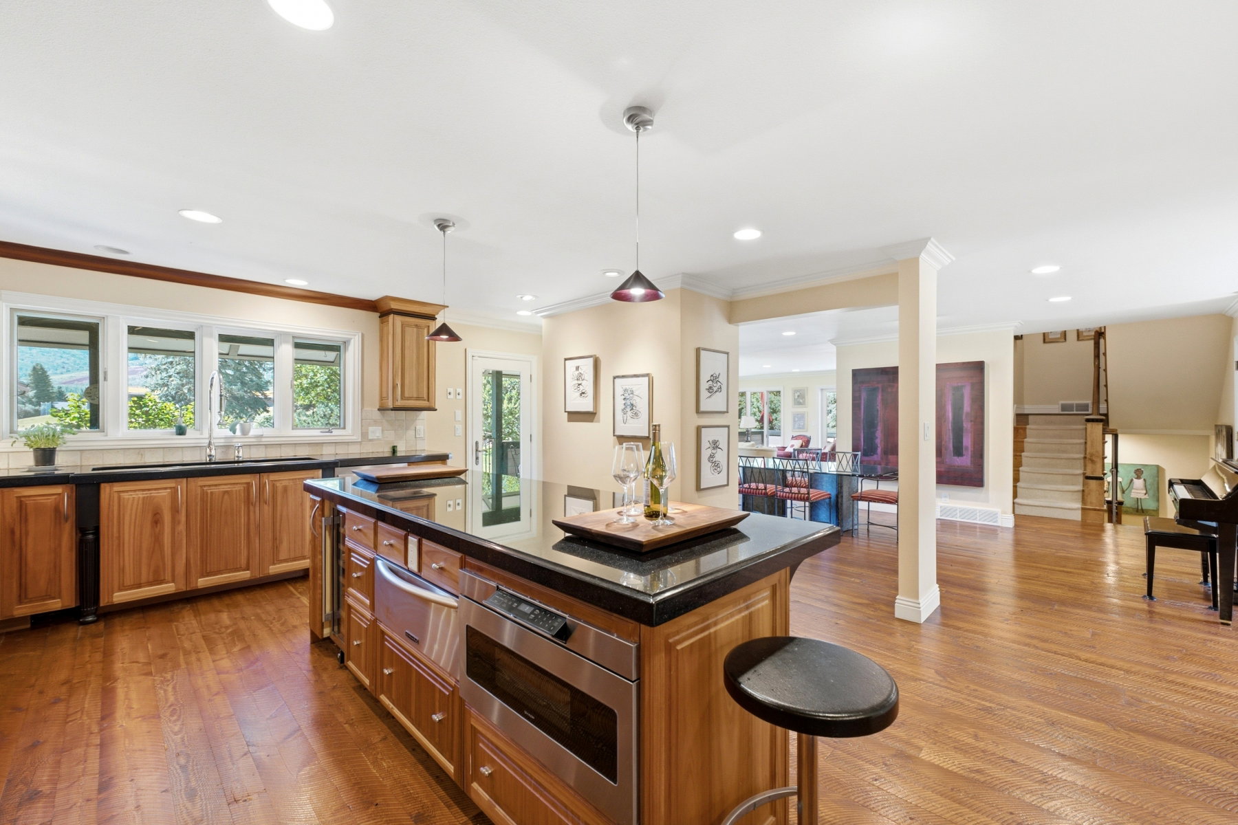 Kitchen featuring a central island with integrated microwave and beverage refrigerator, black countertop, and warm wood-finish cabinetry